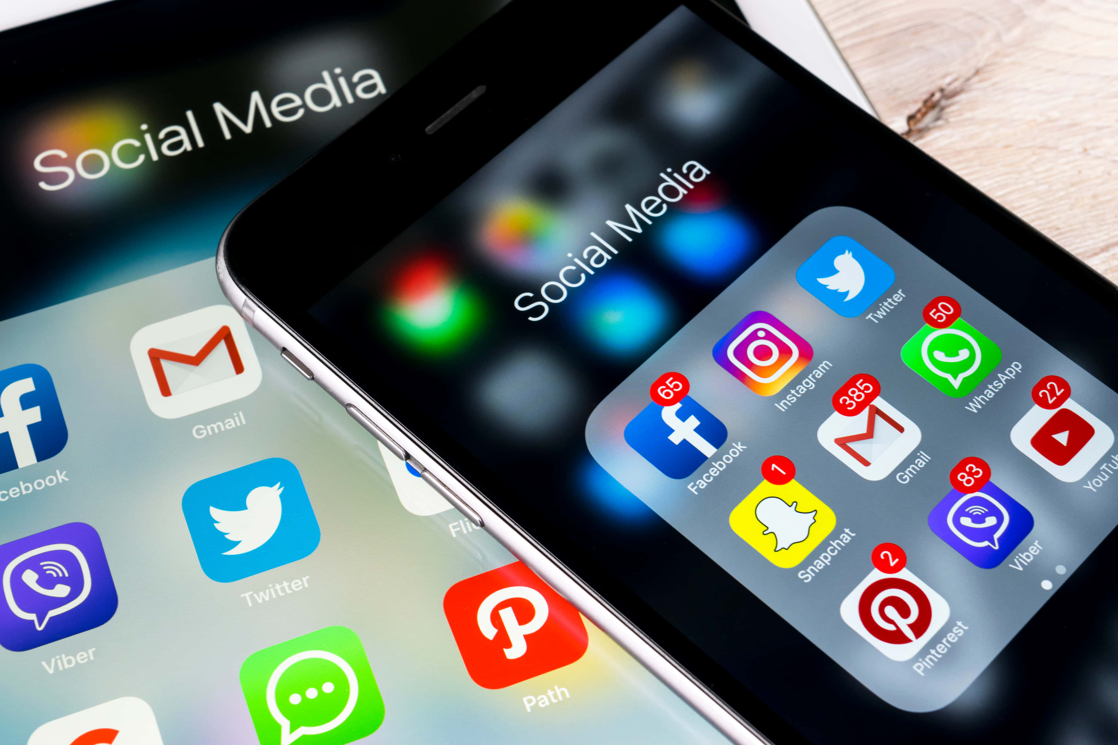 Social Media 桌布 壁紙 — 兩部智能手機在木質表面上顯示帶有通知徽章的社交媒體應用程式圖標。