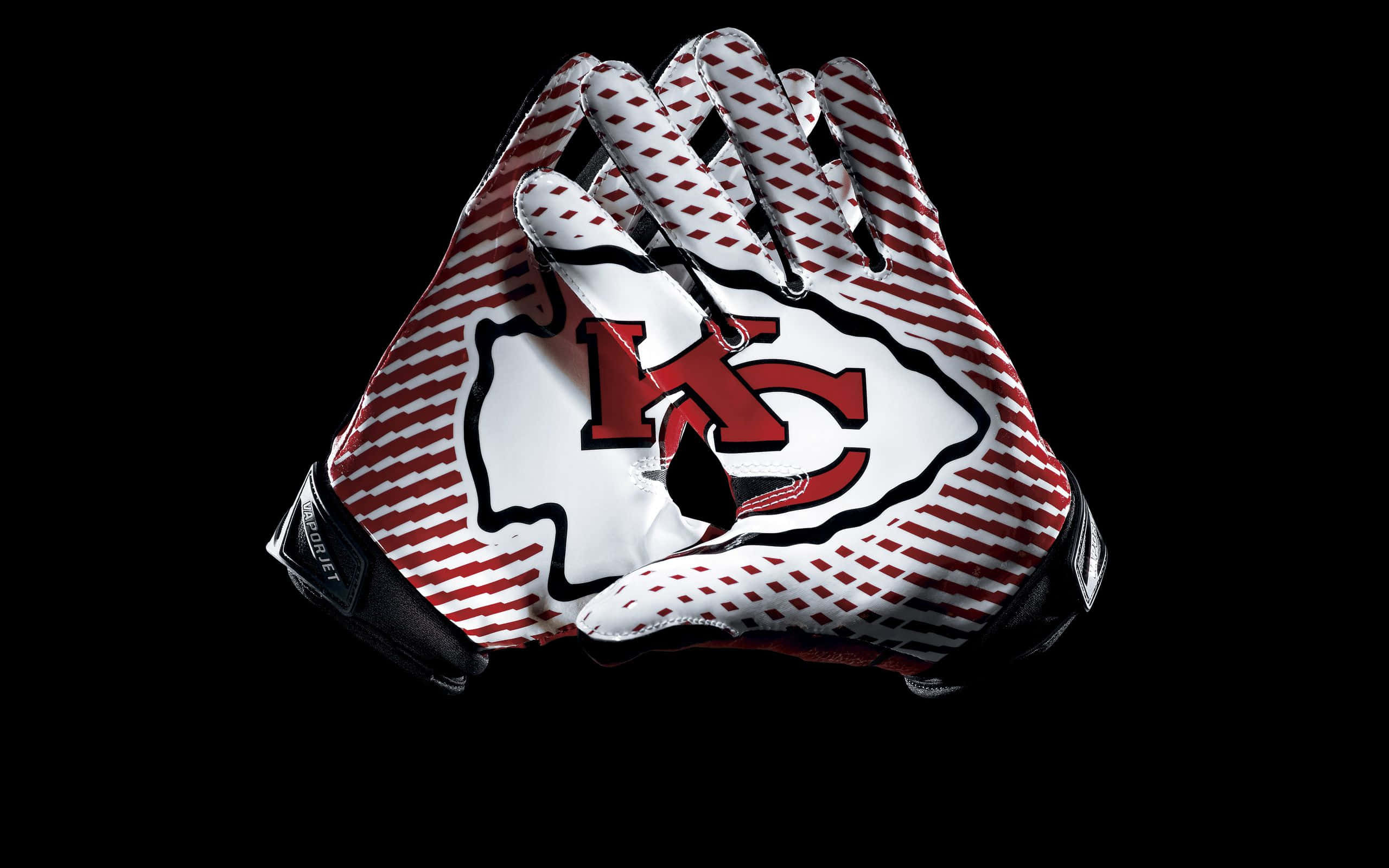 Kansas City Chiefs 桌布 壁紙 — 兩隻堪薩斯城酋長隊美式足球手套，帶有紅白條紋和球隊標誌，在黑色背景上緊握在一起。