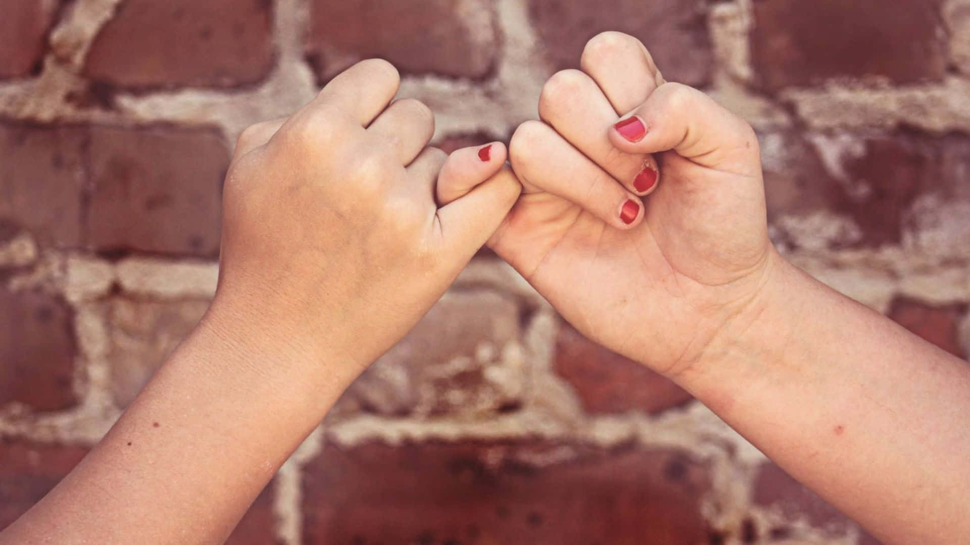 Best Friend 桌布 壁紙 — 兩隻塗有紅色指甲油的手在風化的磚牆前以玩樂式的拳頭碰撞鎖住手指。