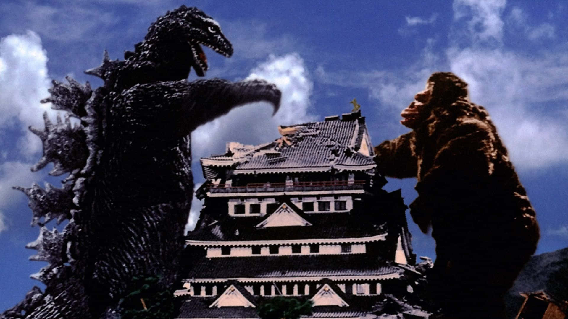 Godzilla Vs Kong 桌布 壁紙 — 兩隻巨型怪物哥斯拉和金剛在傳統日本城堡頂端，在晴朗藍天和蓬鬆雲朵下激烈交鋒。