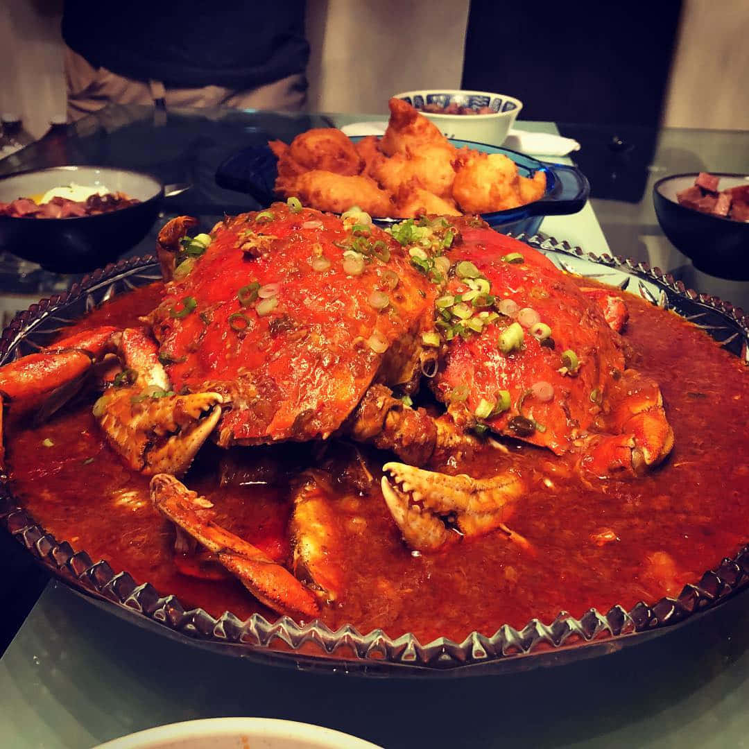 兩隻巨型辣椒蟹 壁紙 — 一盤熱騰騰的辣蟹，配上濃郁的紅醬，撒上蔥花，放在餐桌中央。
