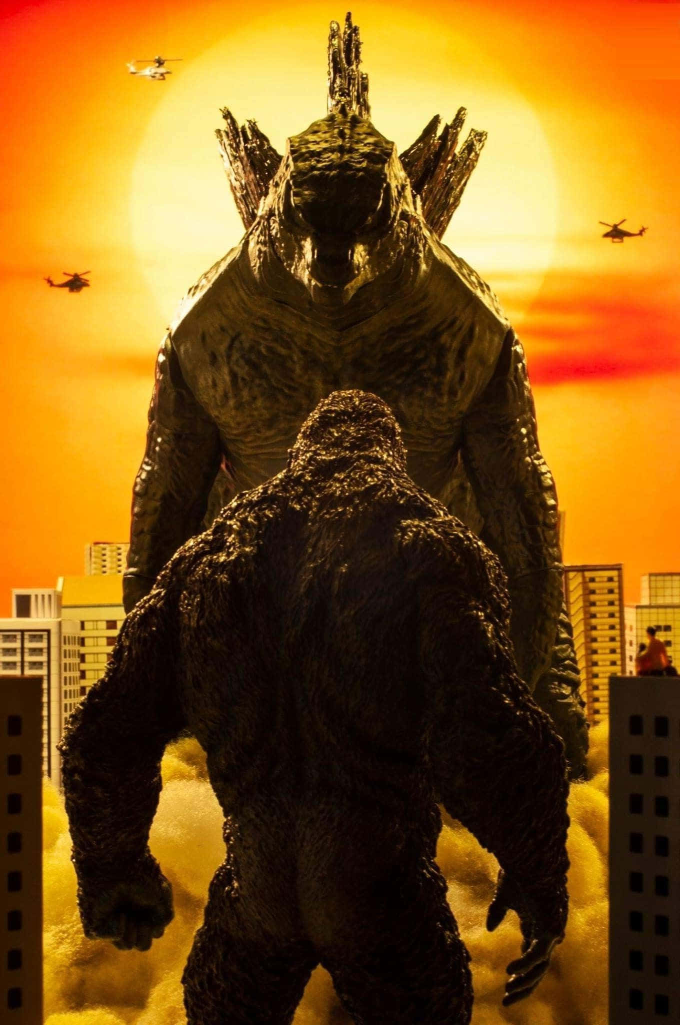Godzilla Vs Kong 桌布 壁紙 — 兩隻巨大怪物哥斯拉和金剛站在城市景觀中，背景是火紅的橙色夕陽，直升機在頭頂飛過。
