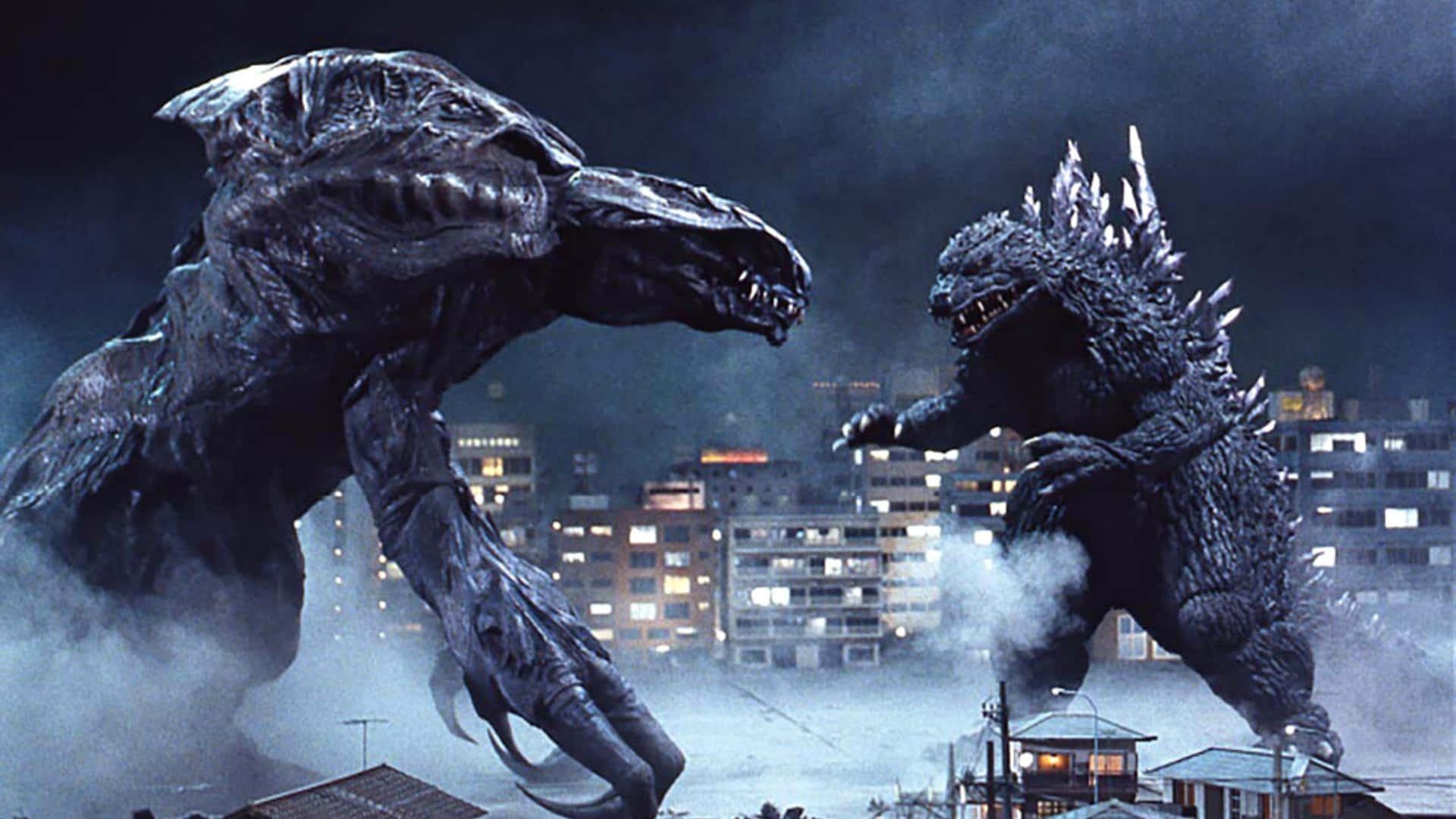 Godzilla 2000 桌布 壁紙 — 兩隻巨大怪獸在煙霧瀰漫的城市夜晚中衝突，背後是閃爍的城市燈光。
