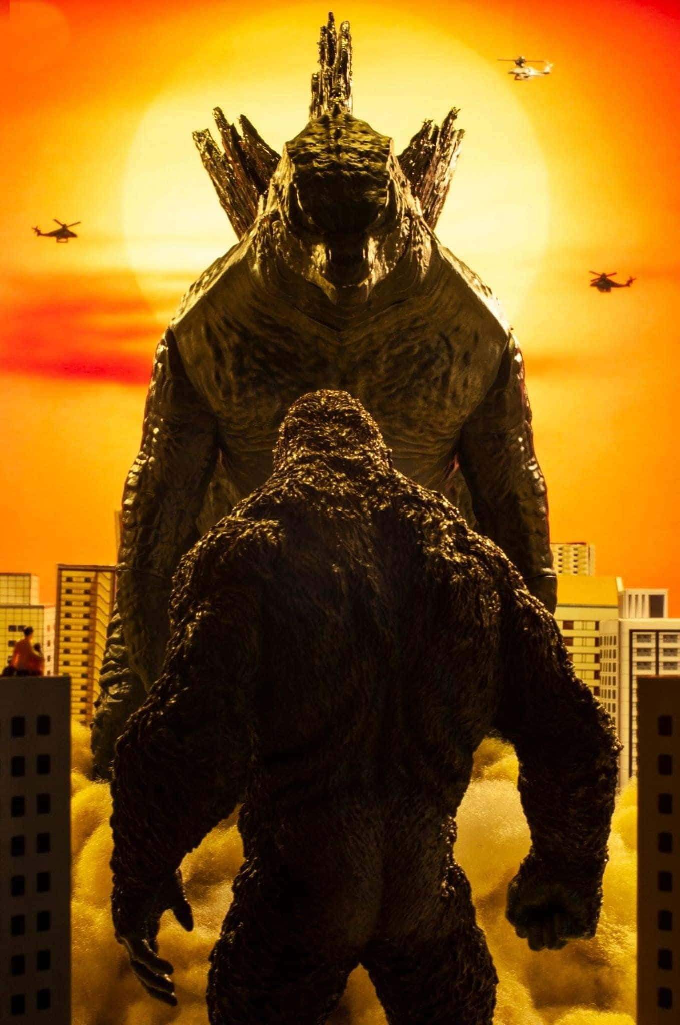 Godzilla Vs Kong 桌布 壁紙 — 兩隻巨獸哥斯拉和金剛在日落時分的城市景觀中對峙，直升機在頭頂飛過。