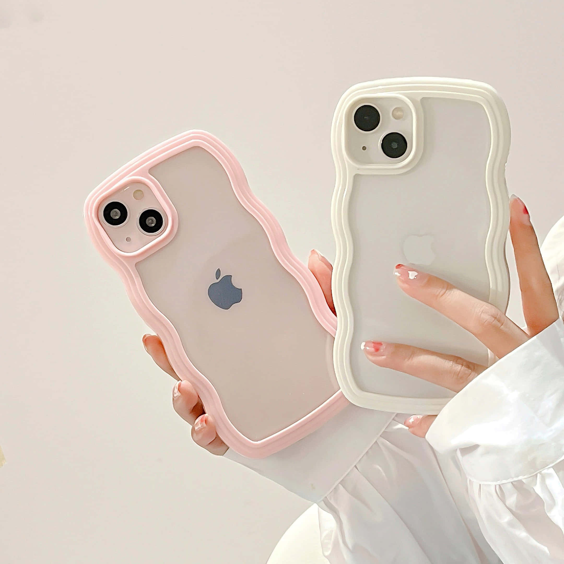 iPhone風格壁紙 桌布 壁紙 — 兩隻手分別拿著時尚波浪邊手機殼，一個粉紅色一個白色，背景係柔和嘅中性色調。