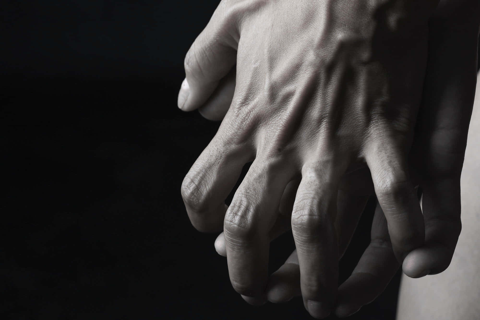 hands 桌布 壁紙 — 兩隻手在純黑背景下緊緊相握，構成戲劇性的單色畫面。