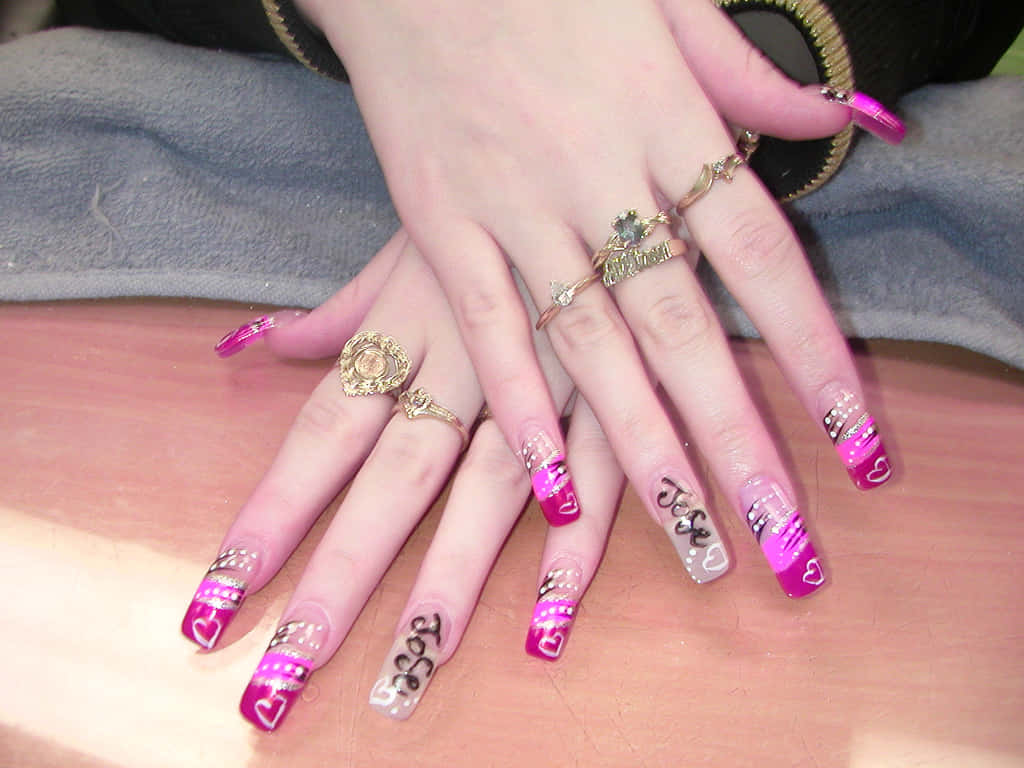 Pink Nails 桌布 壁紙 — 兩隻手帶有閃粉粉紅和白色美甲，飾有心形和文字，放在木質表面上。
