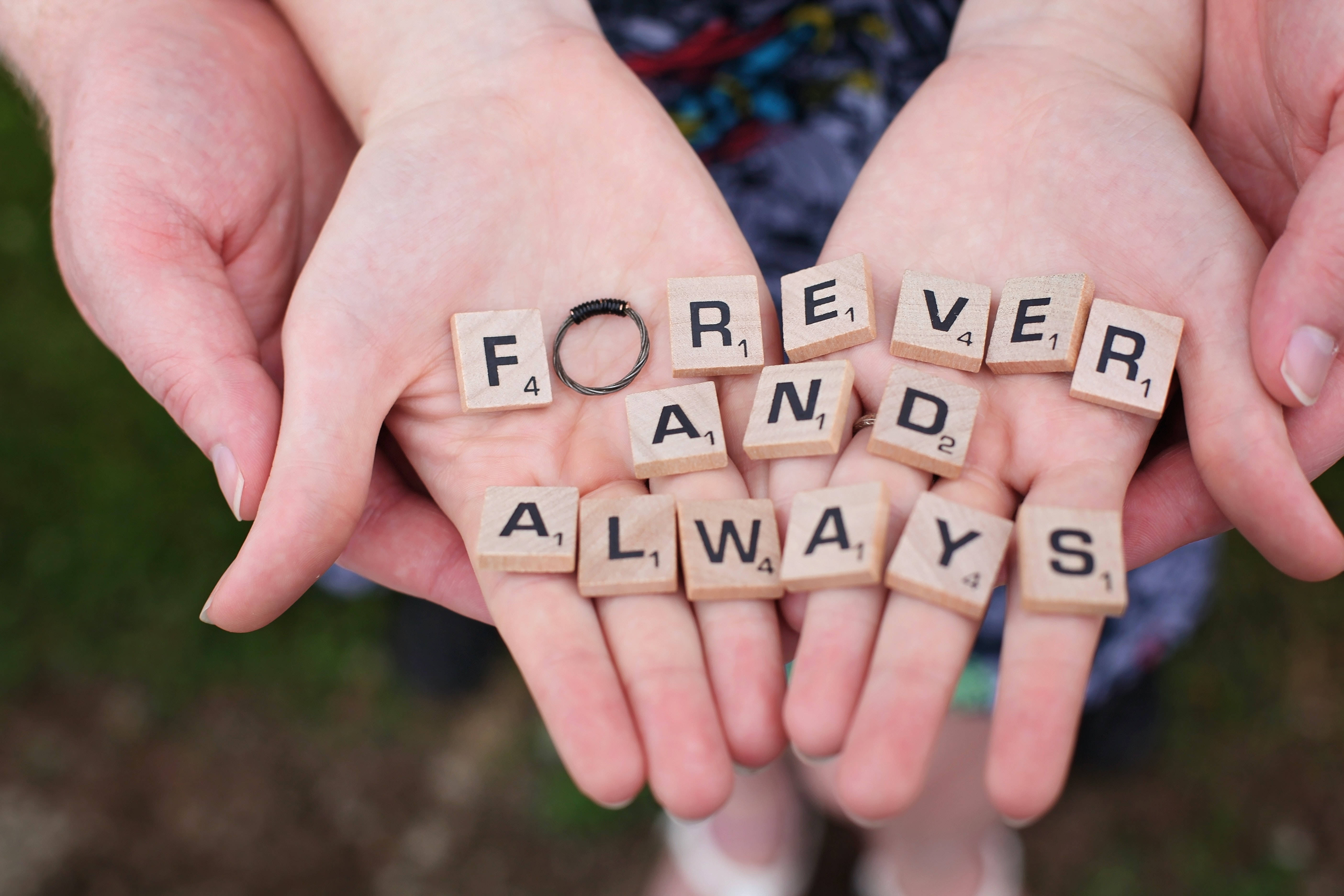 情侶 桌布 壁紙 — 兩隻手捧著木製拼字磚，拼出 forever and always，上面放著一枚結婚戒指。