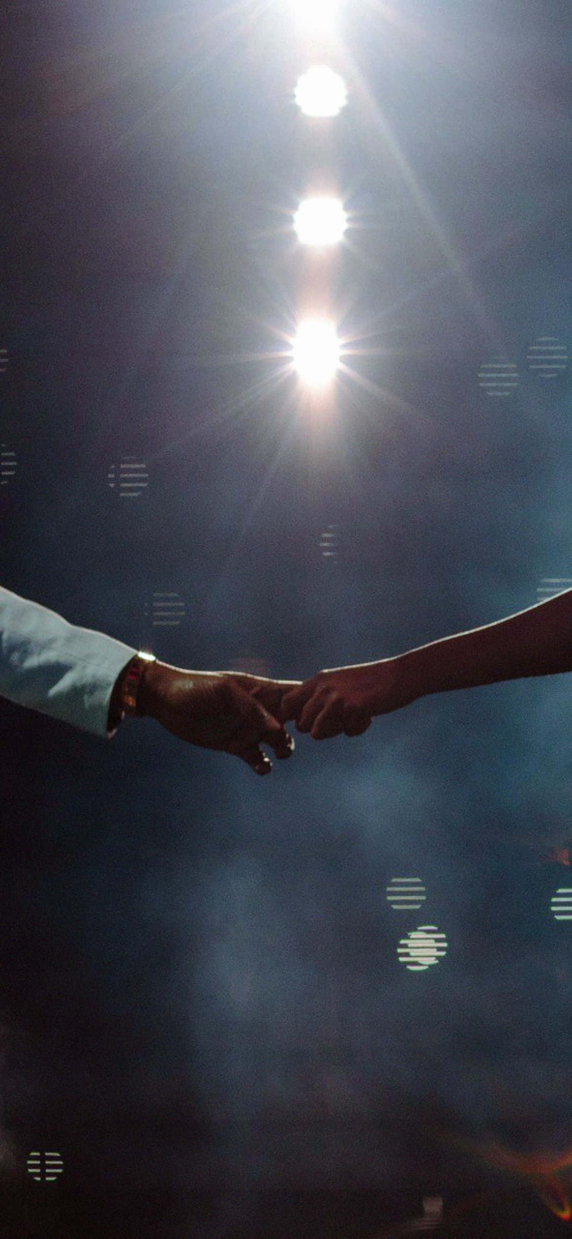 Beyoncé 桌布 壁紙 — 兩隻手穿過黑暗，在明亮的舞台燈光下，伴隨著鏡頭光暈互相觸碰。