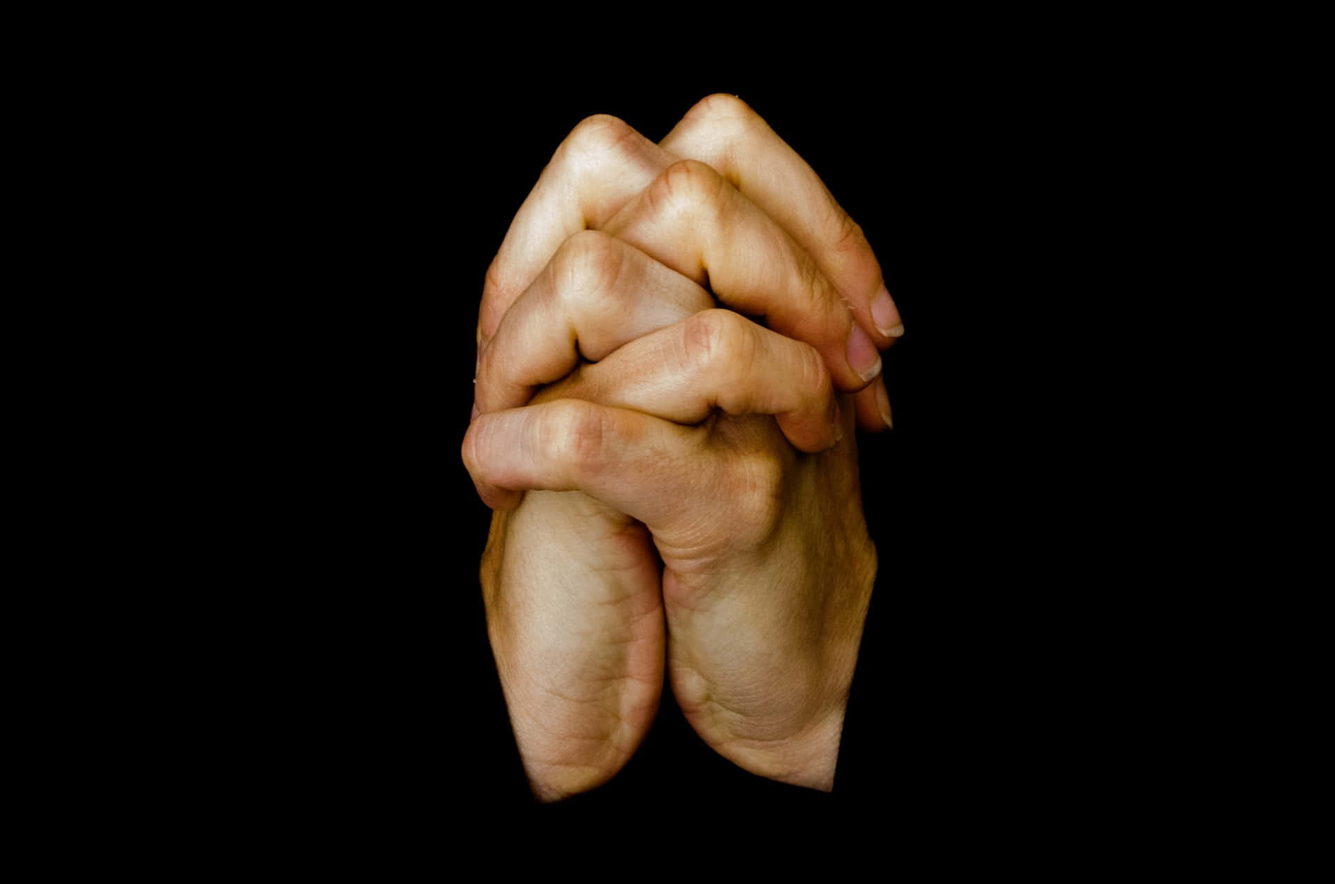 hands 桌布 壁紙 — 兩隻手緊緊握在一起，在純黑背景前做出祈禱或希望的姿勢。