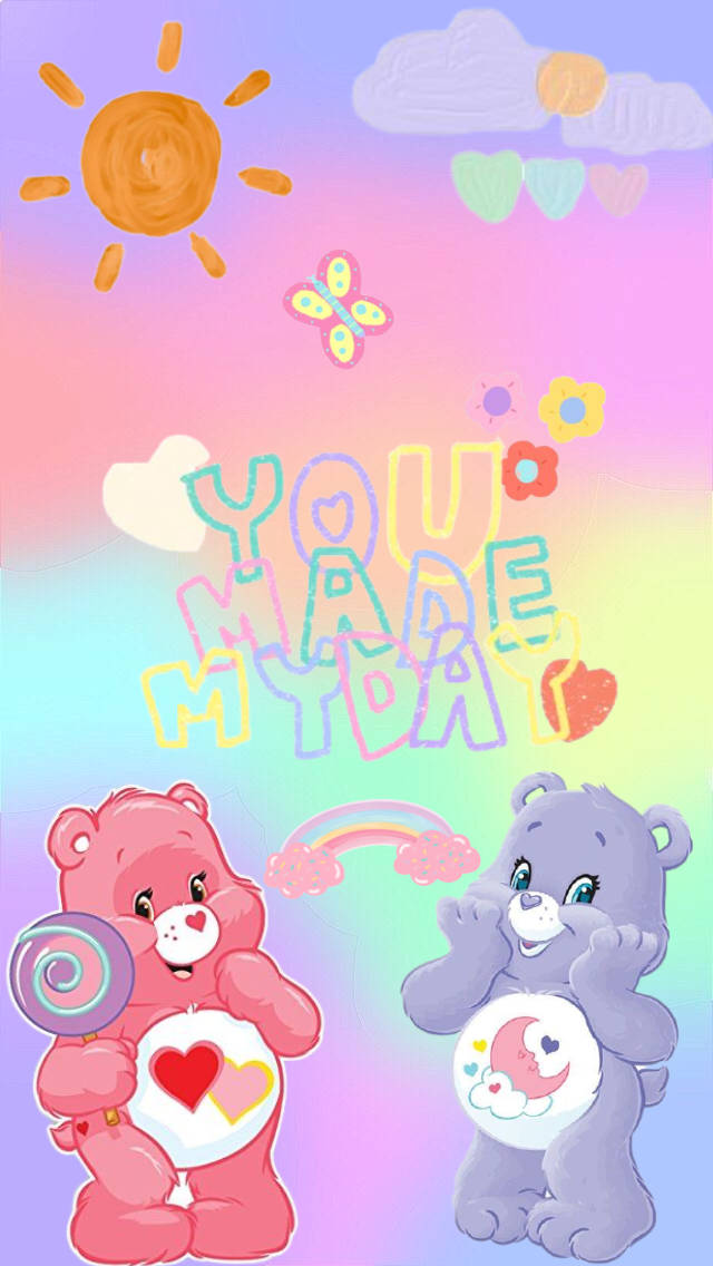 Care Bears 桌布 壁紙 — 兩隻色彩繽紛的Care Bears帶著心心和棒棒糖漂浮在粉彩天空，有太陽雲和彩虹。