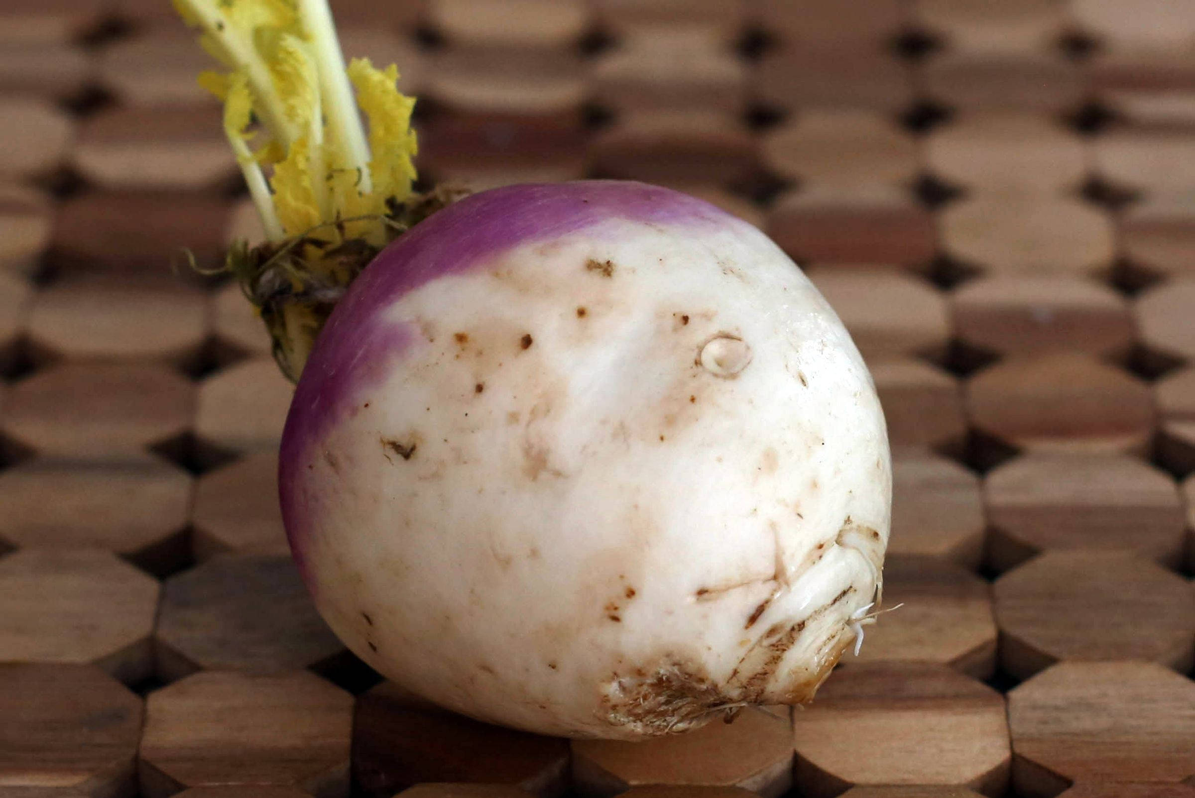八角形木桌上的白蘿蔔 壁紙 — 一個新鮮的紫色頂部蘿蔔放在一個帶有天然木紋紋理的木製六角形墊子上。