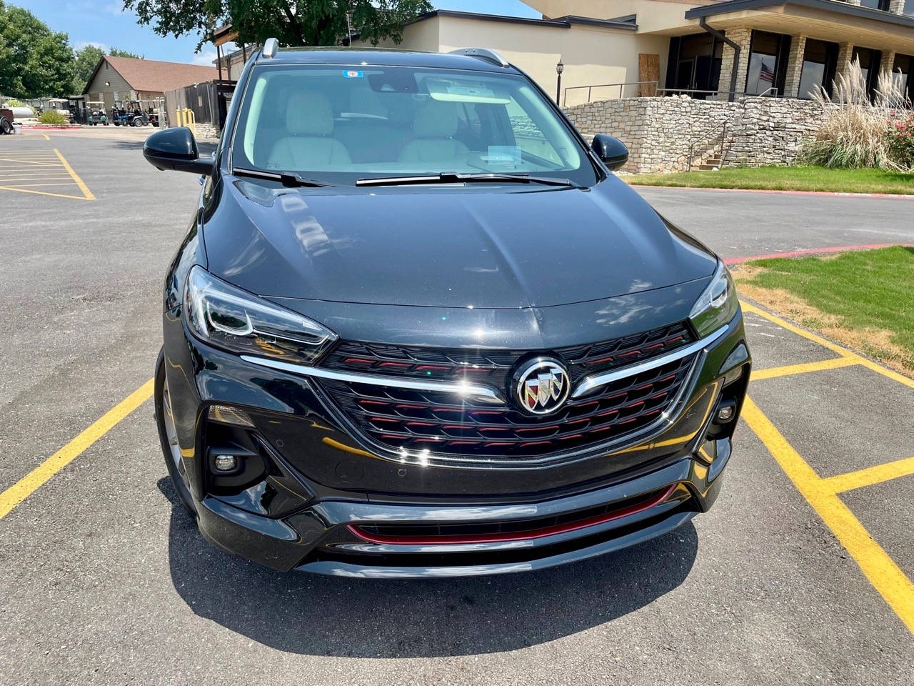 黑色Buick SUV停泊在陽光明媚的停車場，帶有黃線。
