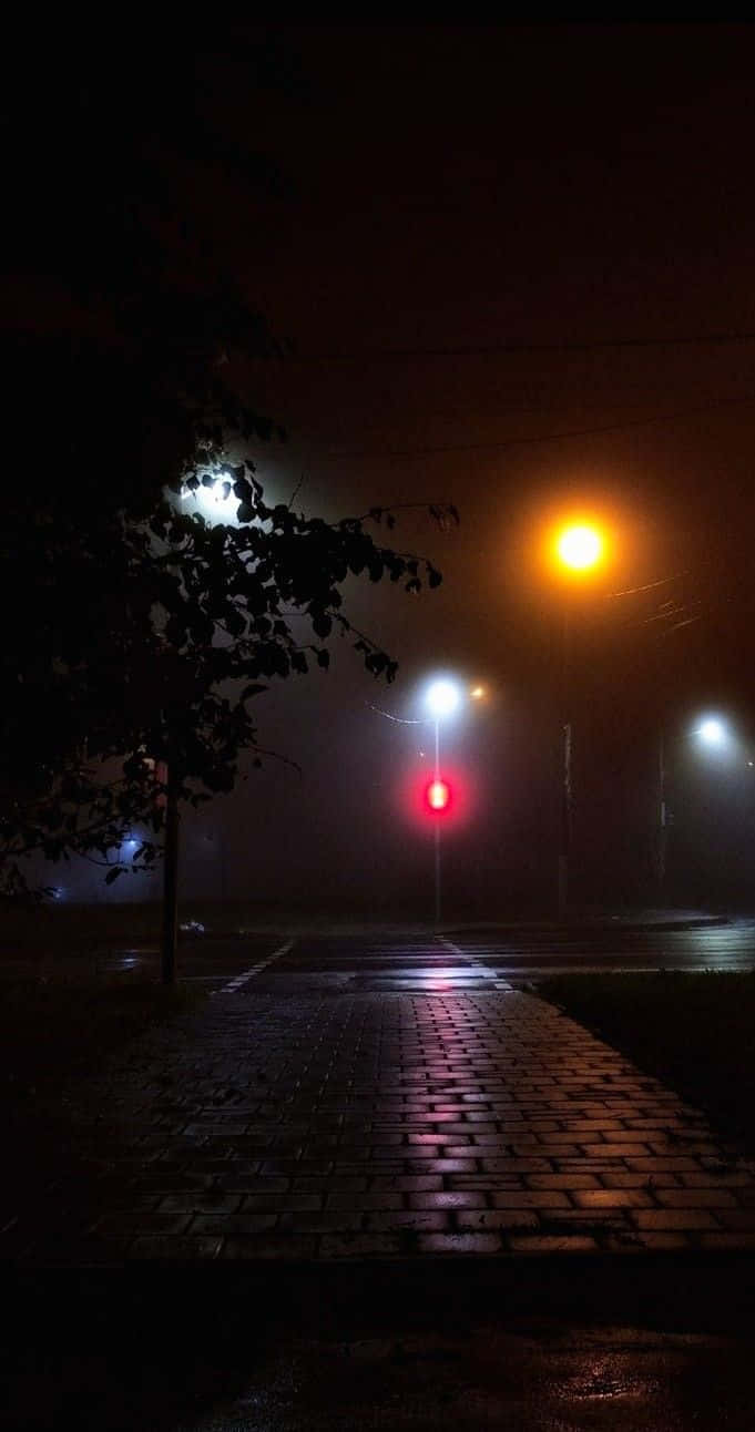 夜晚街道，霧氣瀰漫，發光的街燈在濕漉漉的路面上反射。