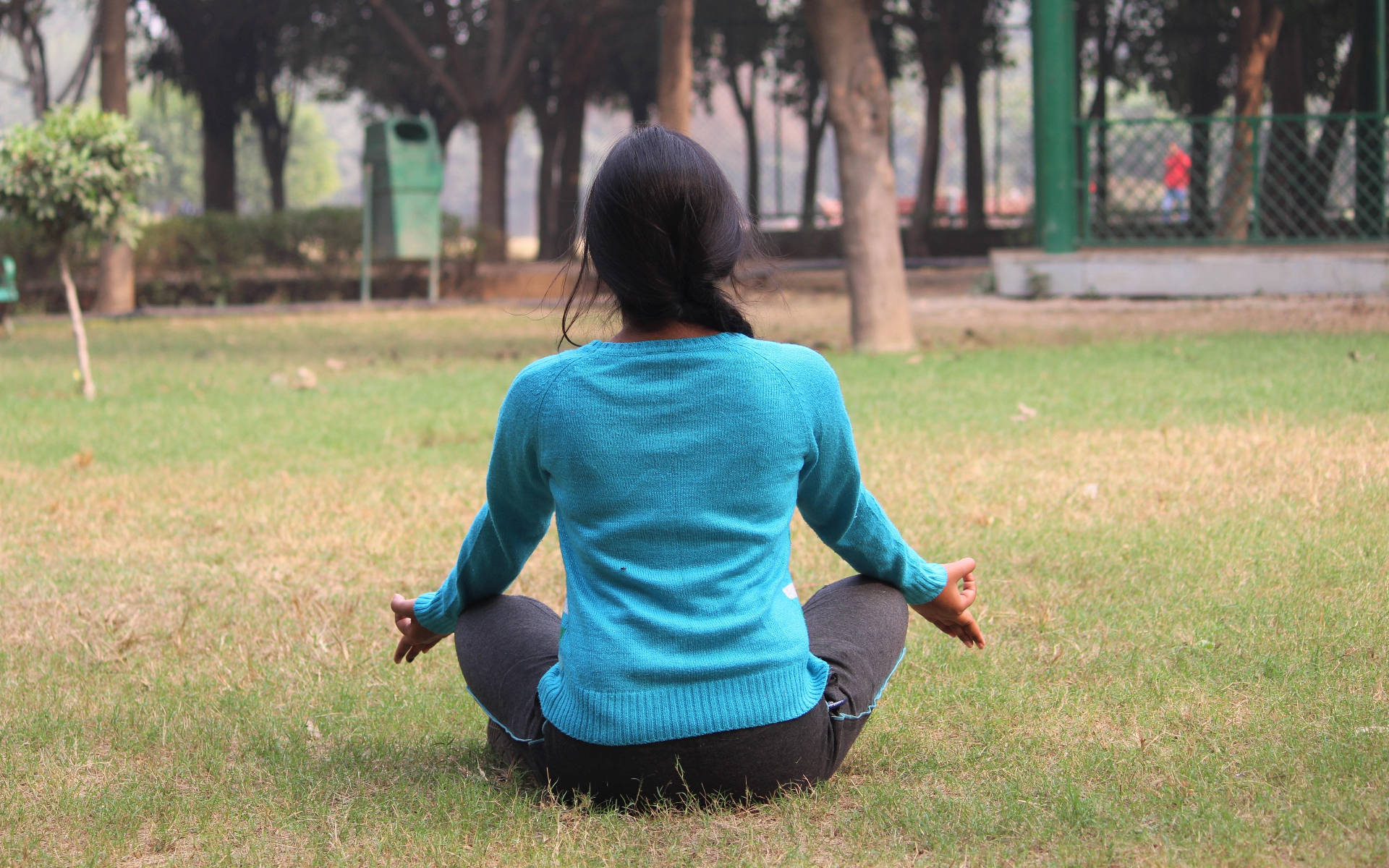 女性在公園草地上盤腿冥想