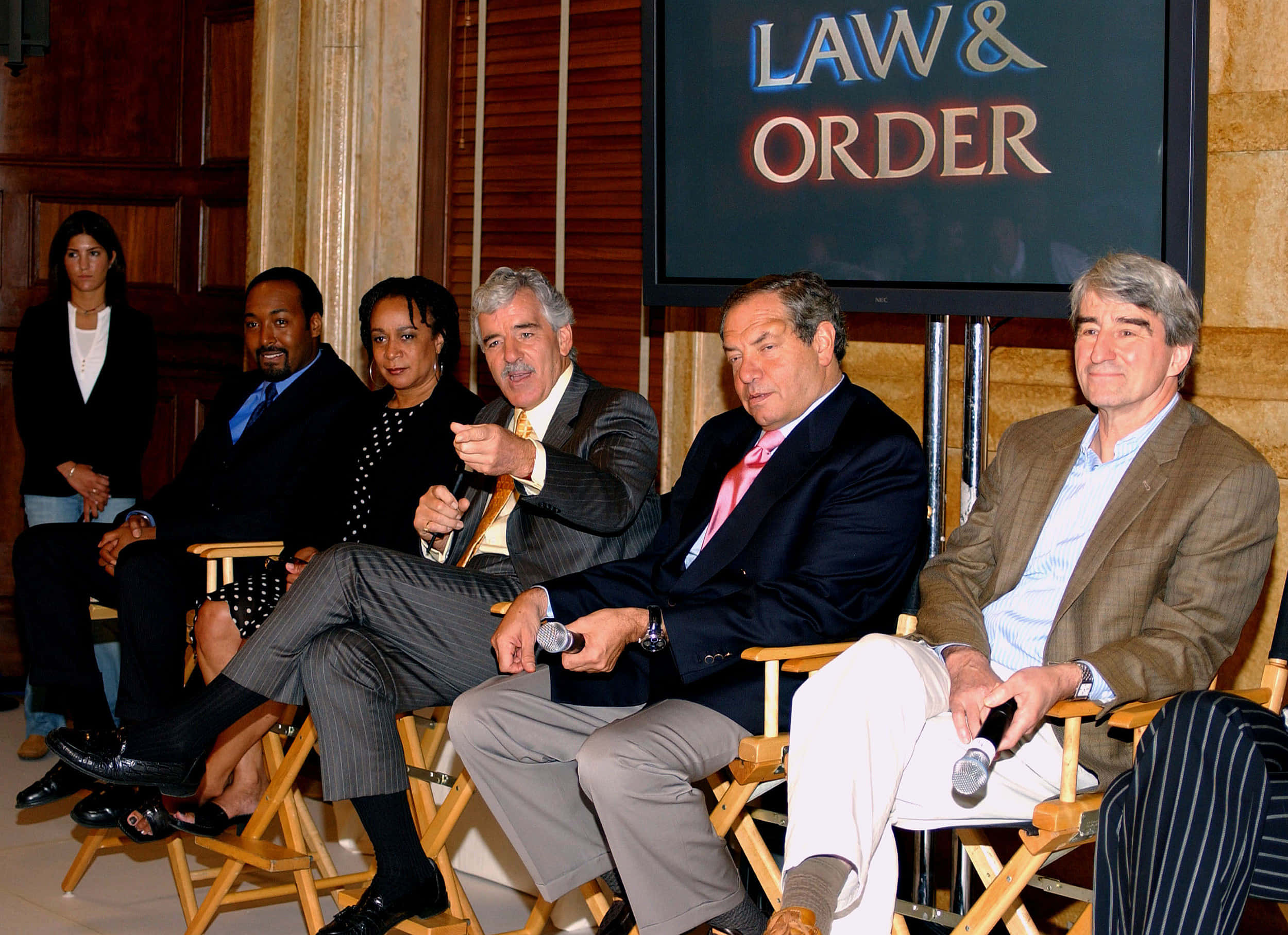 Dennis Farina 桌布 壁紙 — 六位《Law & Order》演員在木鑲板房間的座談會中坐在導演椅上。