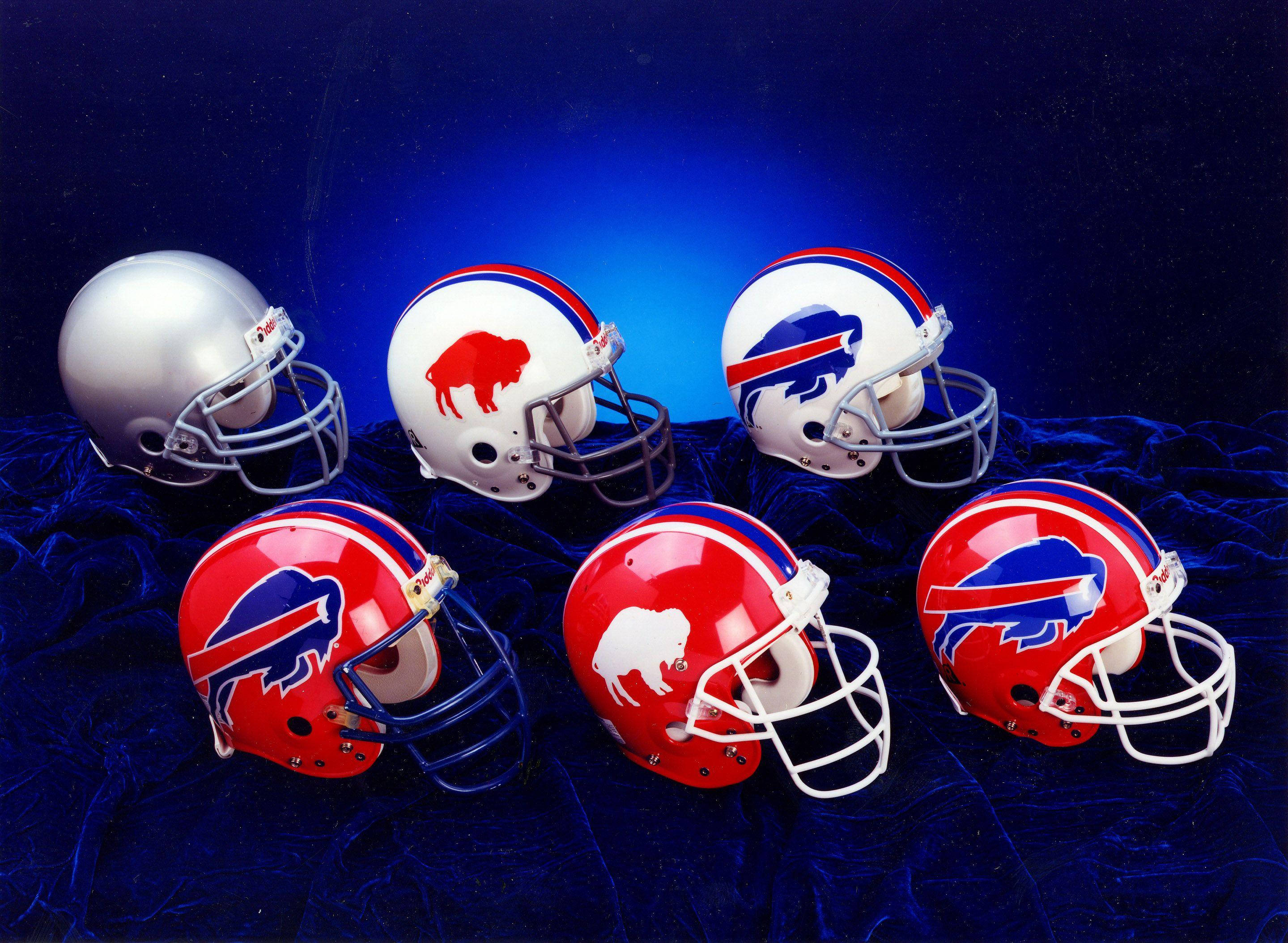 Bills 桌布 壁紙 — 六個不同設計的 Buffalo Bills 美式足球頭盔放置在深藍色天鵝絨上，背景是星空夜晚。