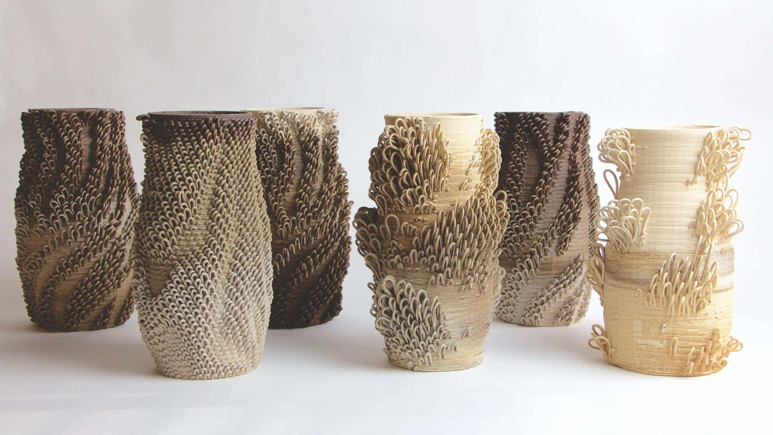 Ceramic 桌布 壁紙 — 六個帶有有機編織圖案、質感複雜的陶瓷花瓶，以大地色調排列在純白色背景前。