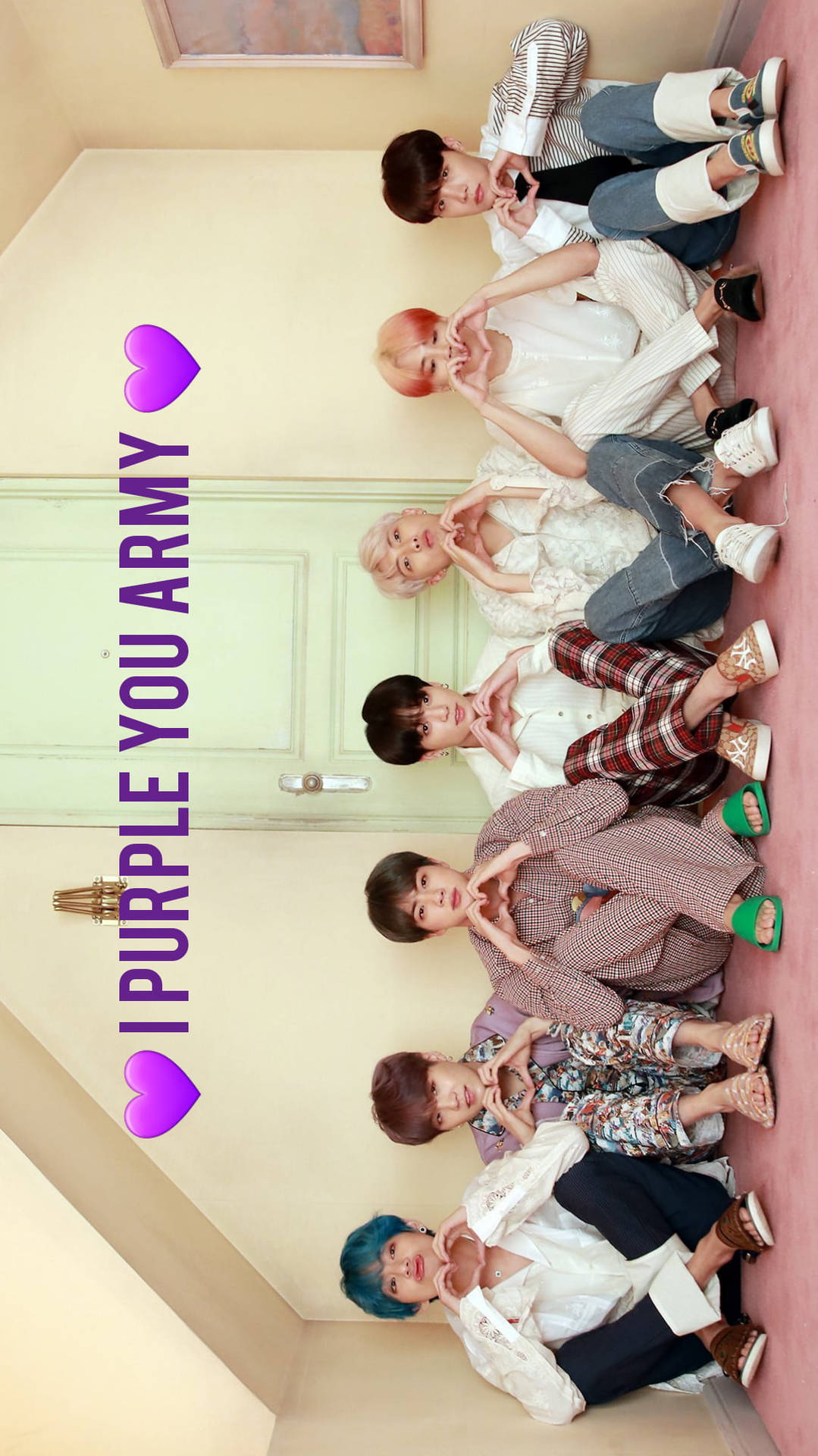 BTS I Purple You Army 壁紙 — 六個有彩色頭髮的年輕男子坐在粉紅色地板上排成一排，對著淡黃色的牆壁用手做出心形。