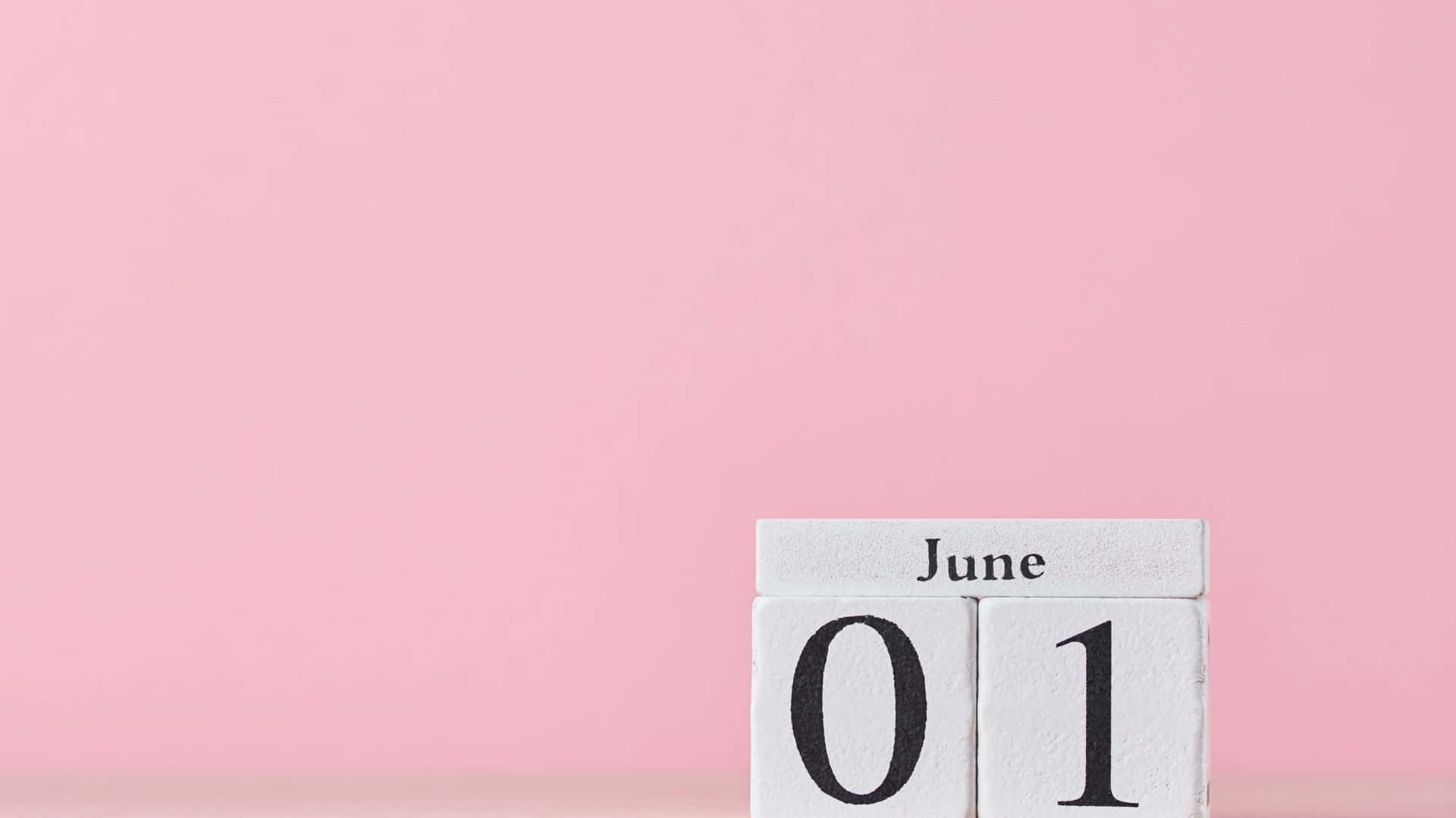白色木製日曆塊，在粉紅色背景上顯示6月1日。