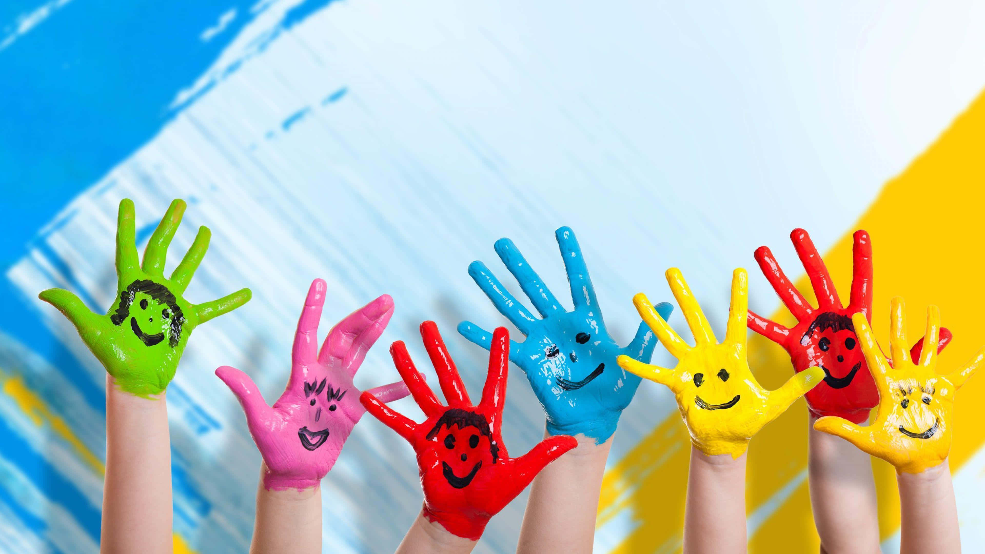 happiness 桌布 壁紙 — 六隻兒童的手塗上鮮豔色彩，每隻都有一個笑臉，在充滿活力的抽象背景前舉起。