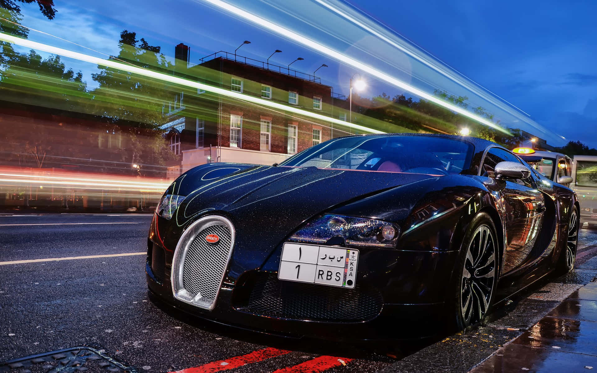 黑色Bugatti Veyron停泊在濕滑街道上，背景是模糊的城市燈光於黃昏。