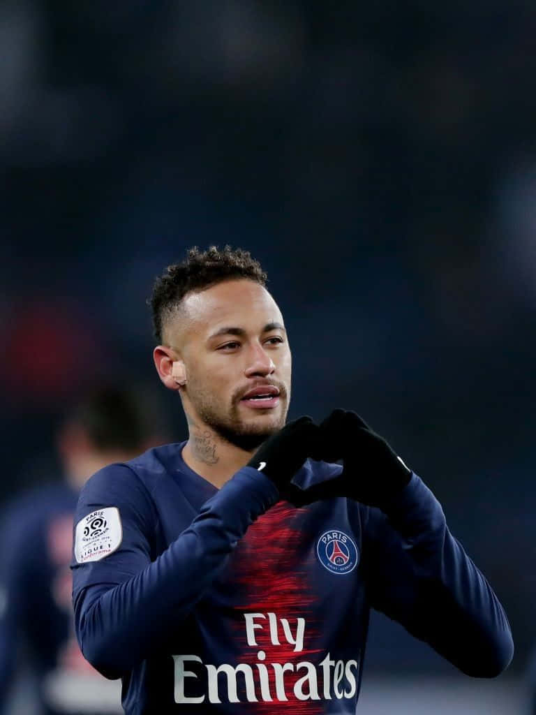 内马尔對陣巴塞羅那主罰自由球 壁紙 — 足球員尼馬（Neymar Jr）戴上手套，雙手比心，身穿巴黎聖日耳曼球衣，在球場燈光下。