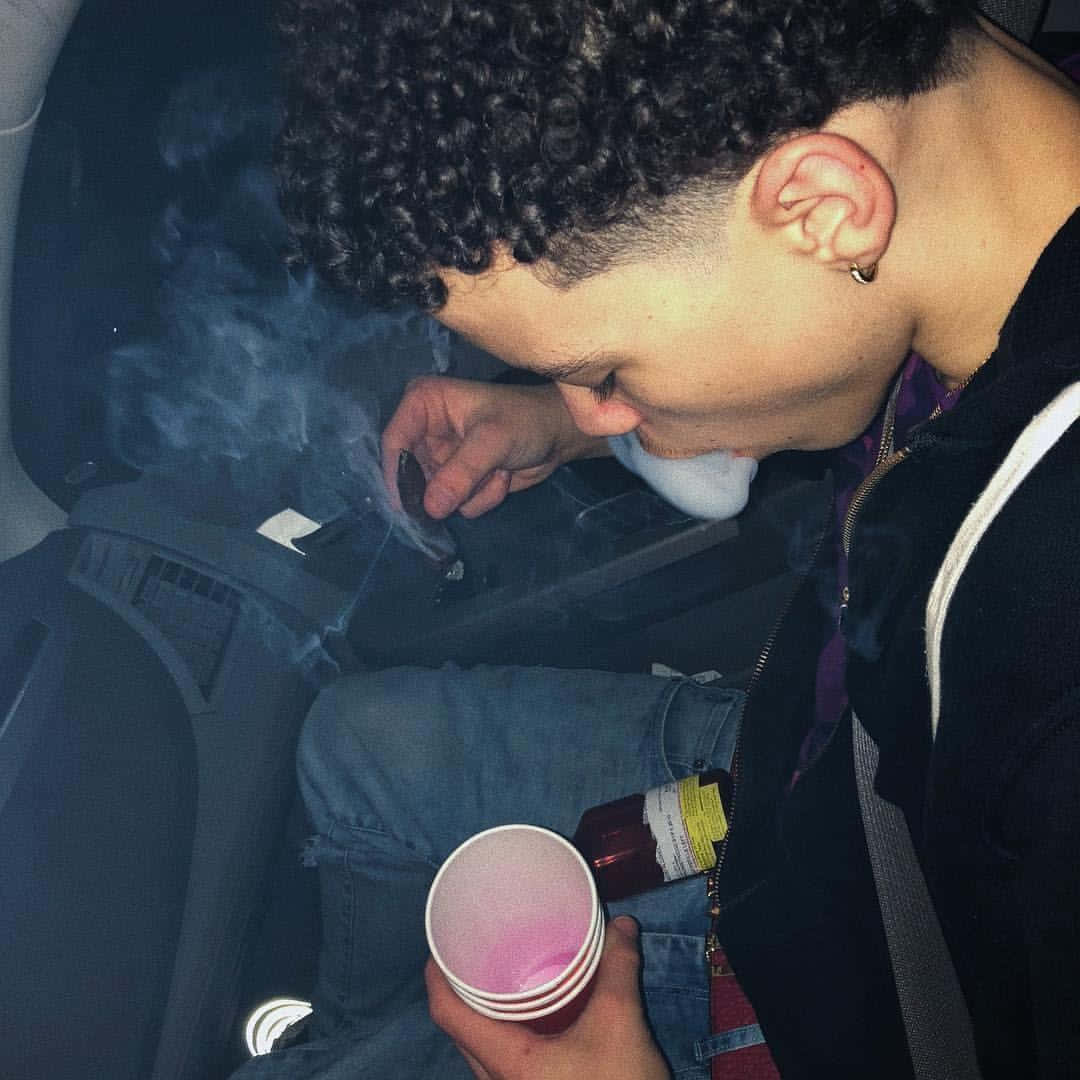 夜間在車內吸煙的人手持粉紅色杯子和瓶子