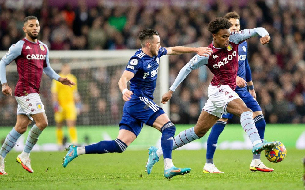 冉冉升起的足球新星卡尼·丘庫埃梅卡 壁紙 — 身穿栗色和藍色球衣的足球運動員在體育場燈光下，在充滿活力的綠色球場上激烈爭奪一個彩色足球。