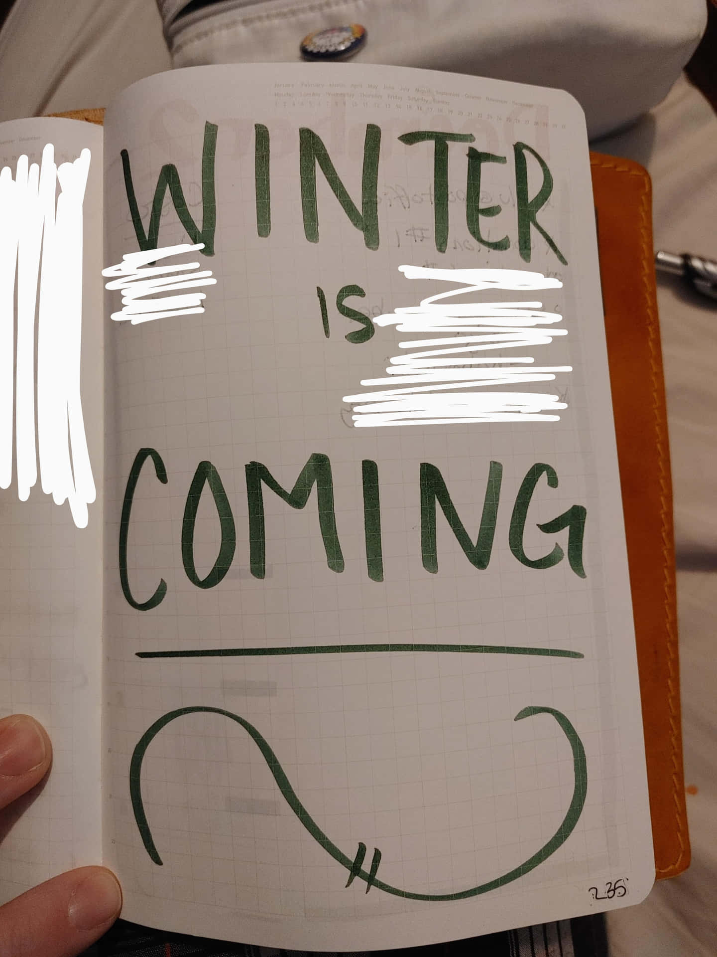 手拿筆記本，「WINTER IS COMING」文字部分被白色塗鴉遮蓋。