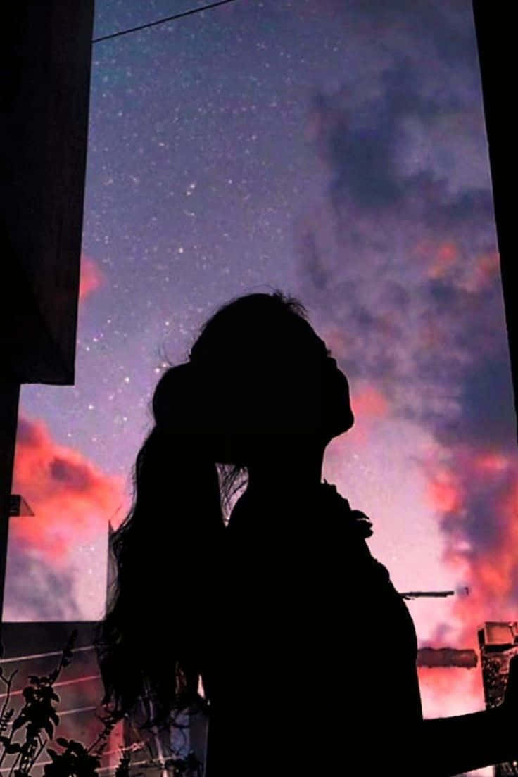 一個人的剪影仰望星空，天空有紫色和橙色的雲彩。