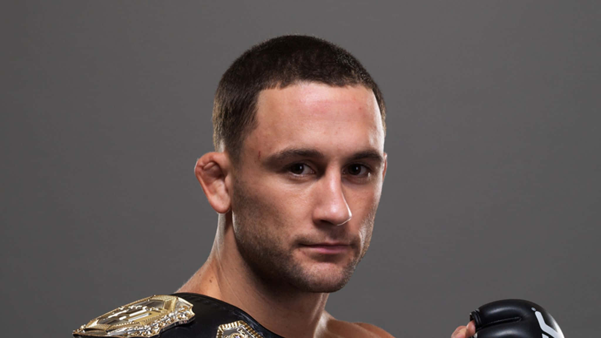 冠軍的堅定目光 - UFC 選手弗蘭基·愛德華 壁紙 — 一位專注的混合武術家，帶著冠軍腰帶和拳擊手套，背景為中性灰色。