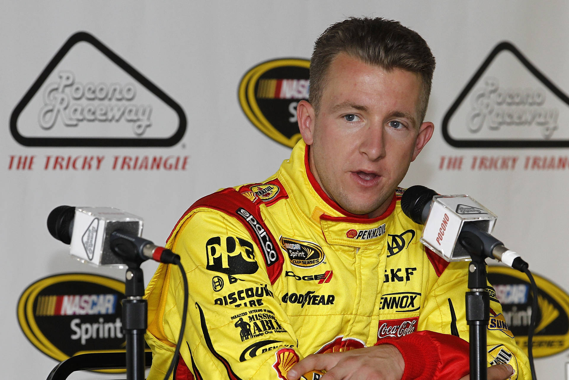 身穿黃色賽車服的NASCAR車手在記者會上發言。