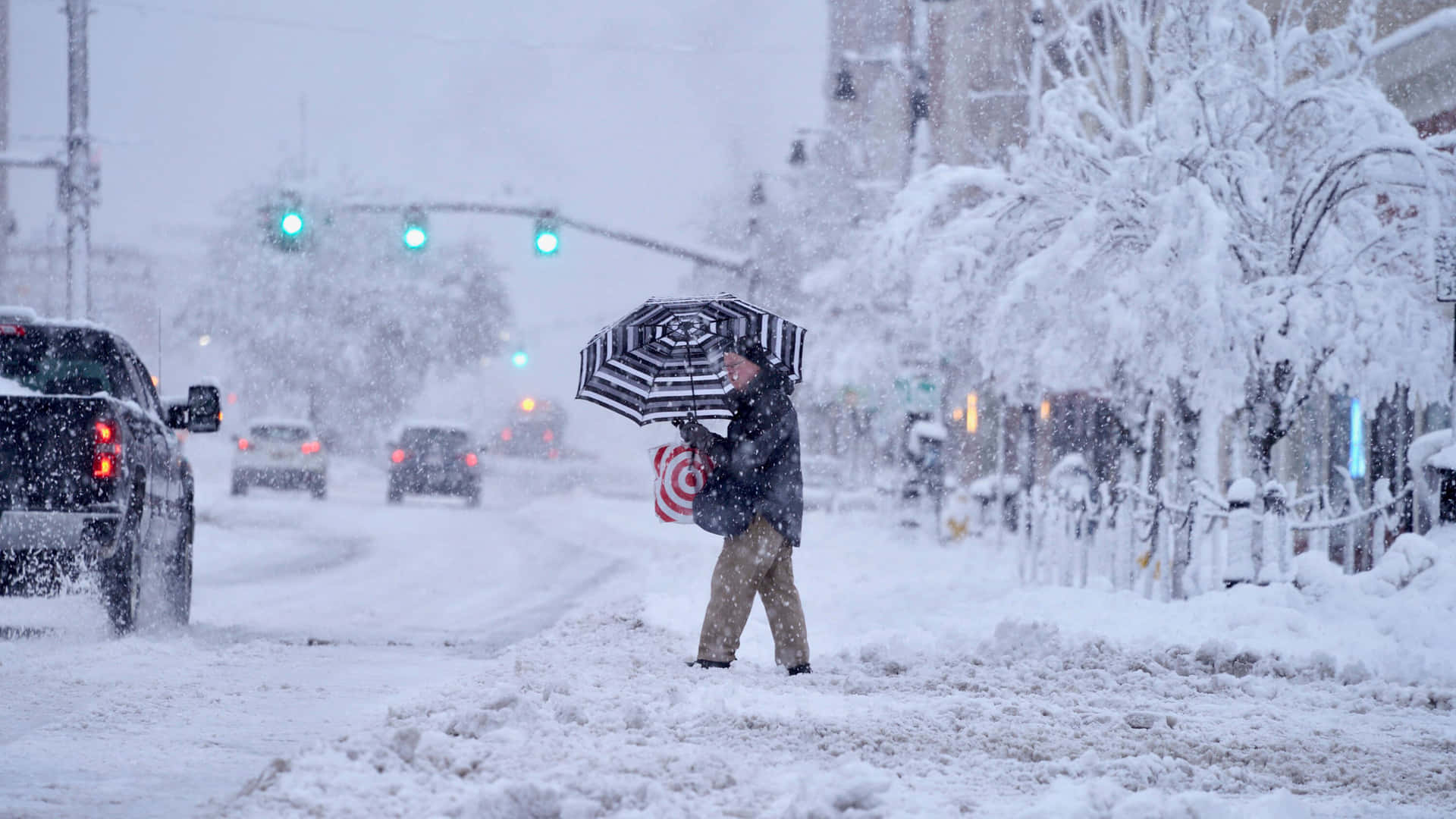 在冬季風暴中撐傘穿過積雪街道的人。