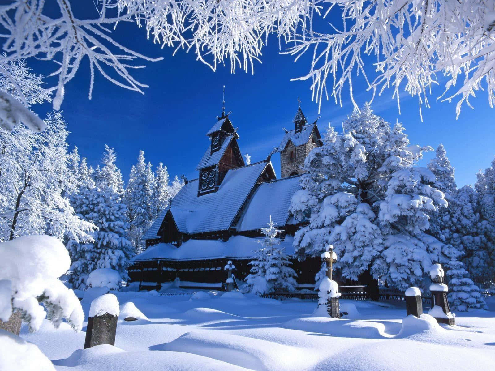 冬季仙境 壁紙 — 一座被雪覆蓋的木製教堂，帶有精緻雕刻，在霜凍樹枝框住的鮮豔藍天下寧靜矗立。