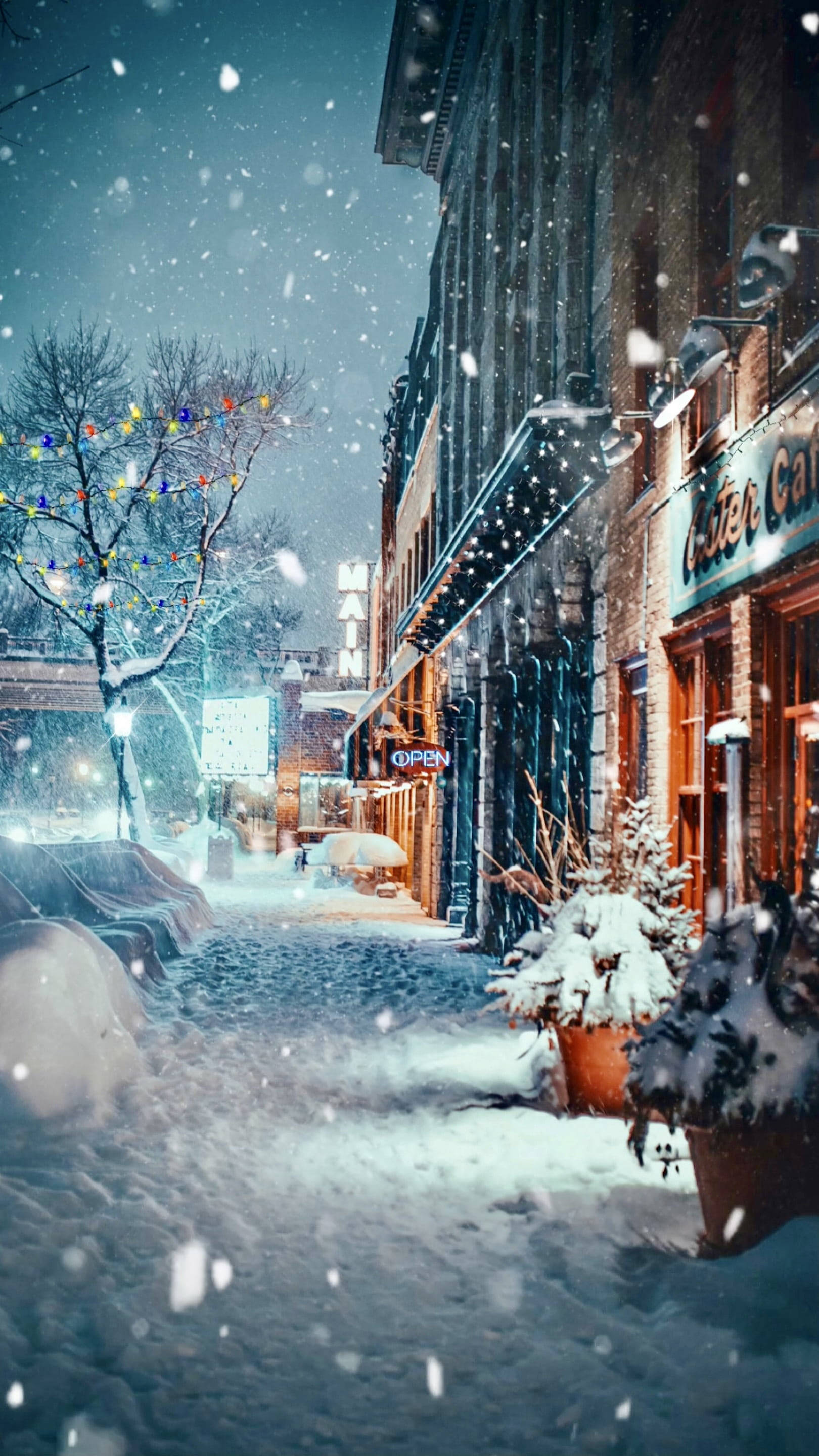冬季假期銀色閃耀場景 壁紙 — 雪花飄過一條舒適的冬季街道，兩旁是溫暖照明的磚砌建築和節日燈飾。