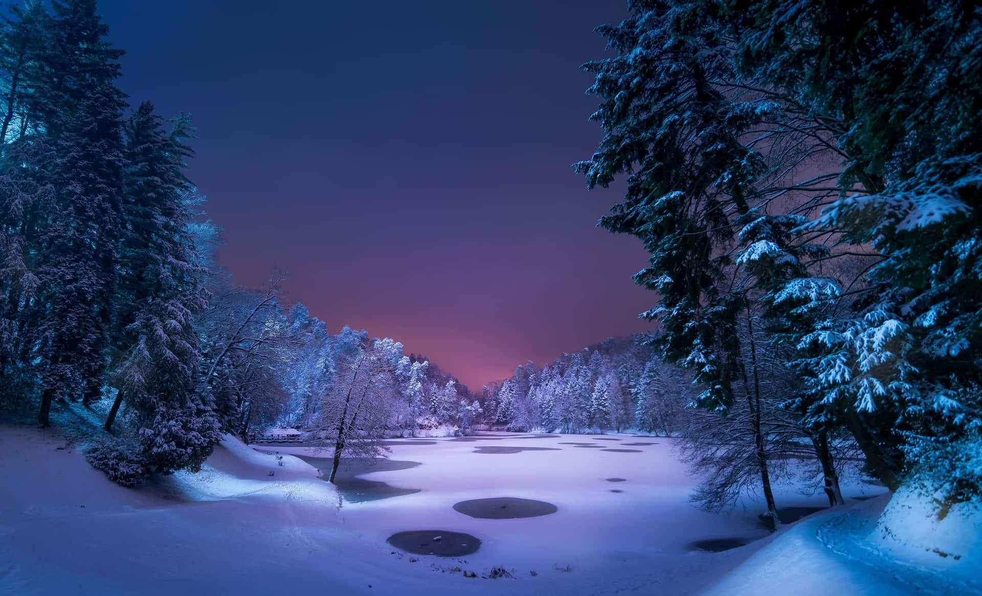 暮色中白雪覆蓋的森林湖泊，紫色和藍色天空