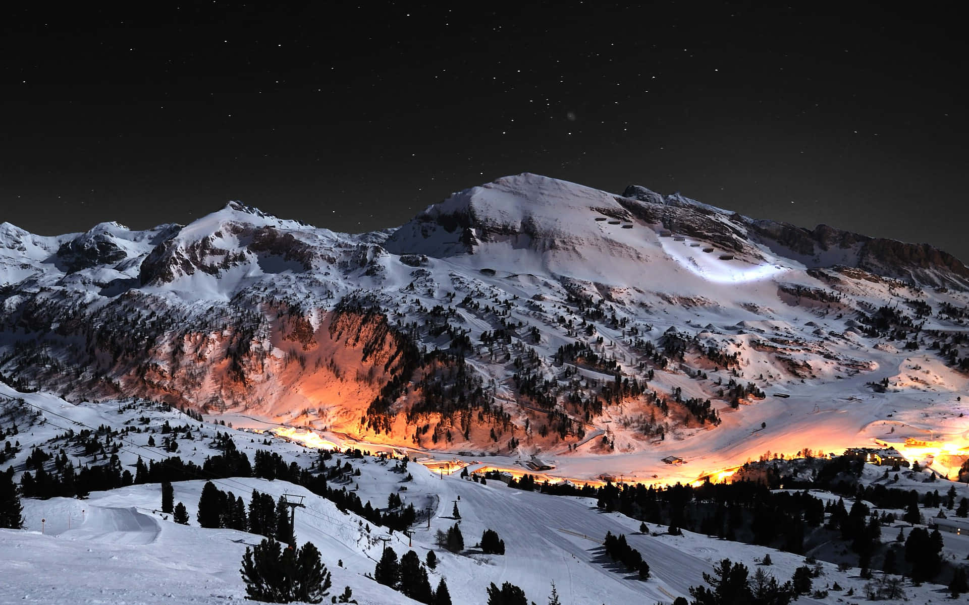 星空下白雪覆蓋的山峰，山谷中燈光閃爍
