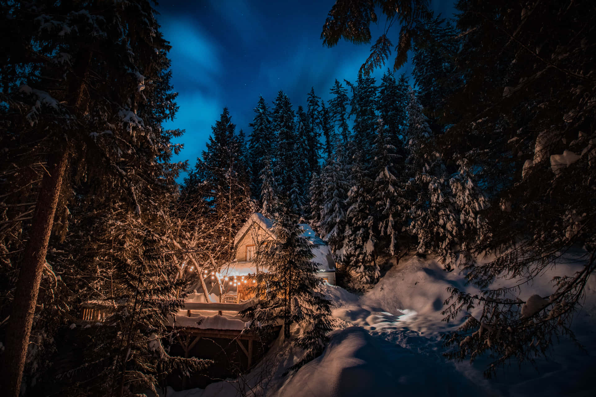 冬季森林中積雪覆蓋的小屋，夜晚散發溫暖光芒。