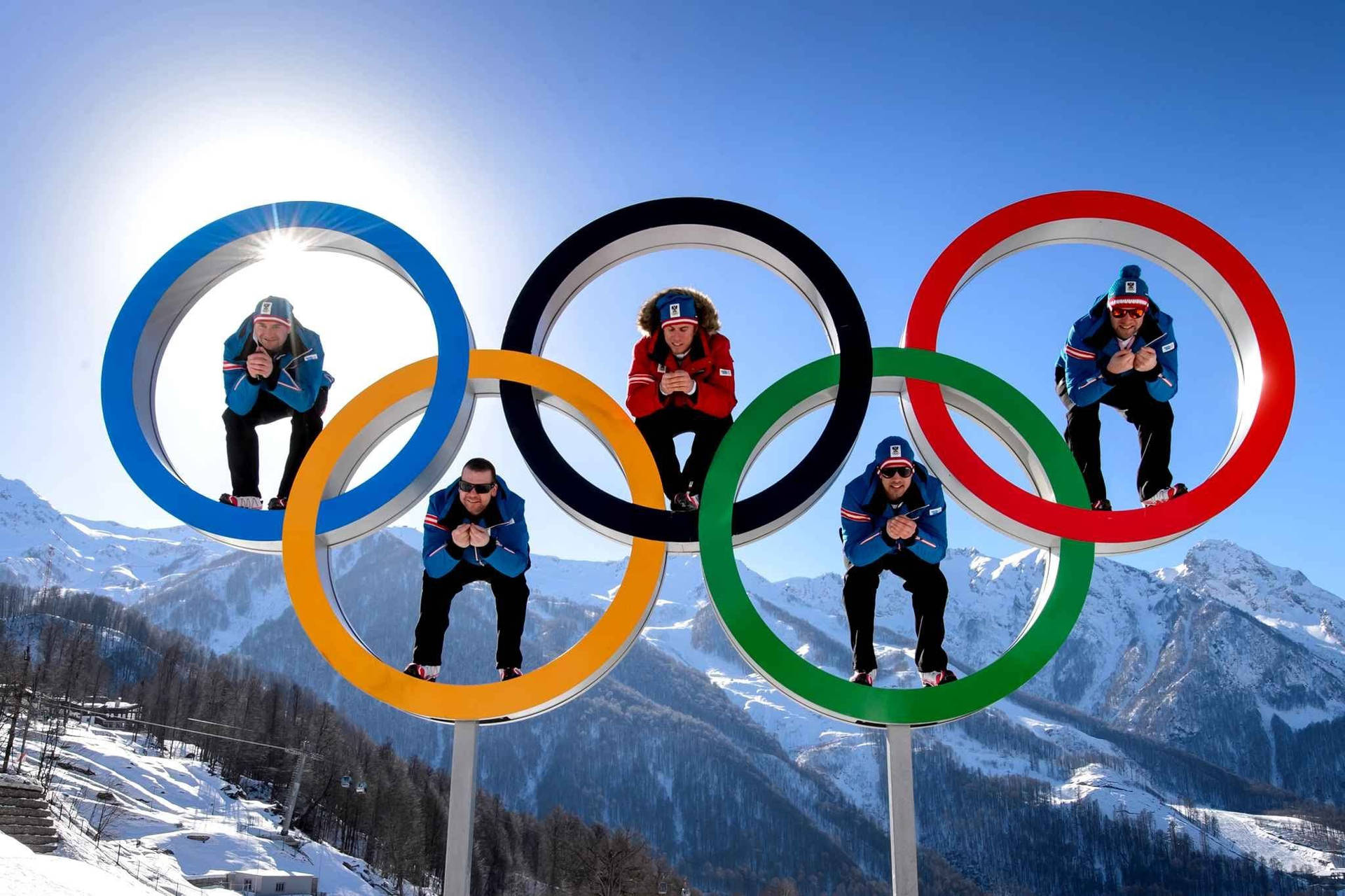 五名運動員在白雪覆蓋的山上於奧運五環內擺姿勢。