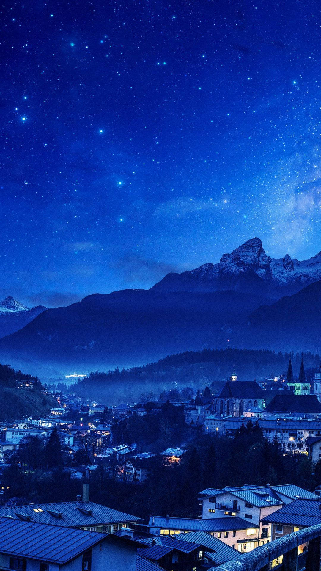 山城在星空夜空下，窗戶發光，山峰積雪。