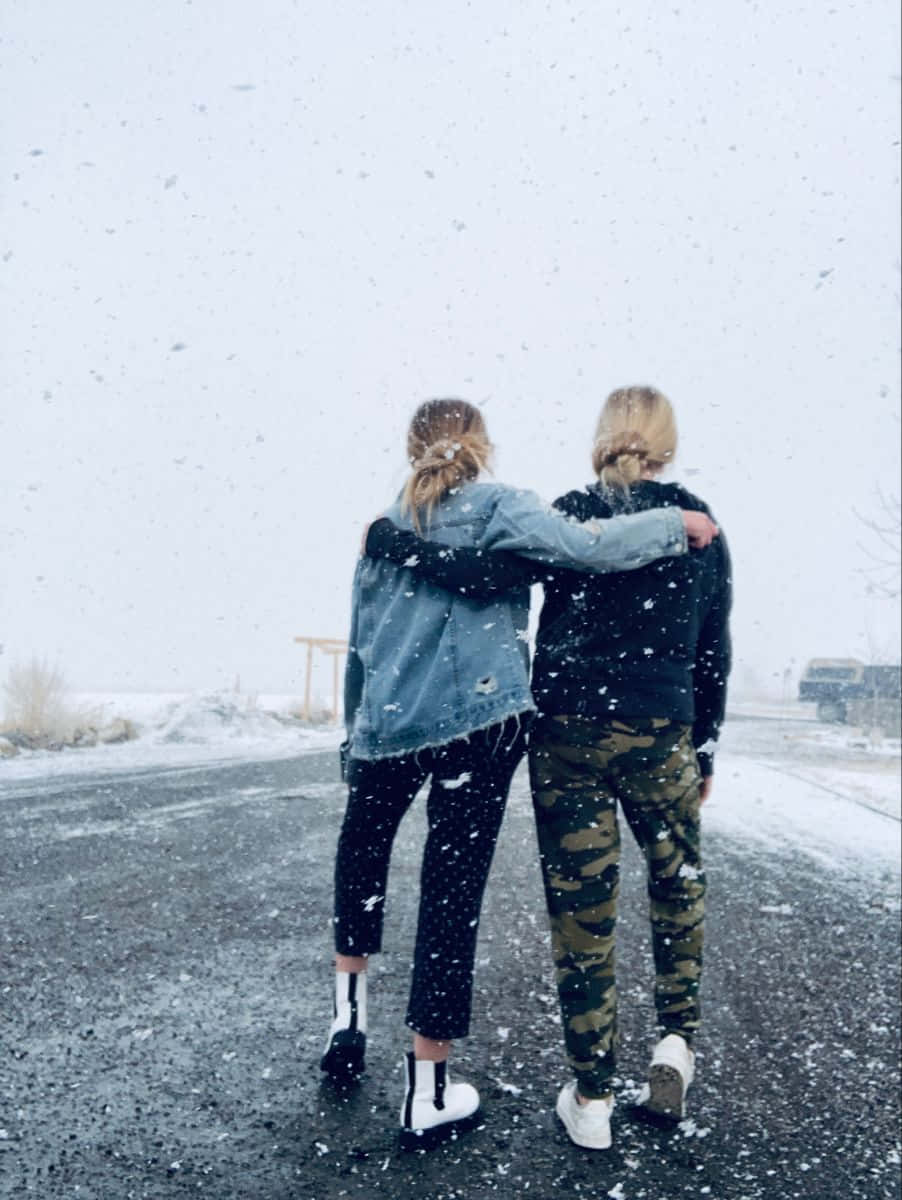 兩個人在雪路上穿著冬裝擁抱。
