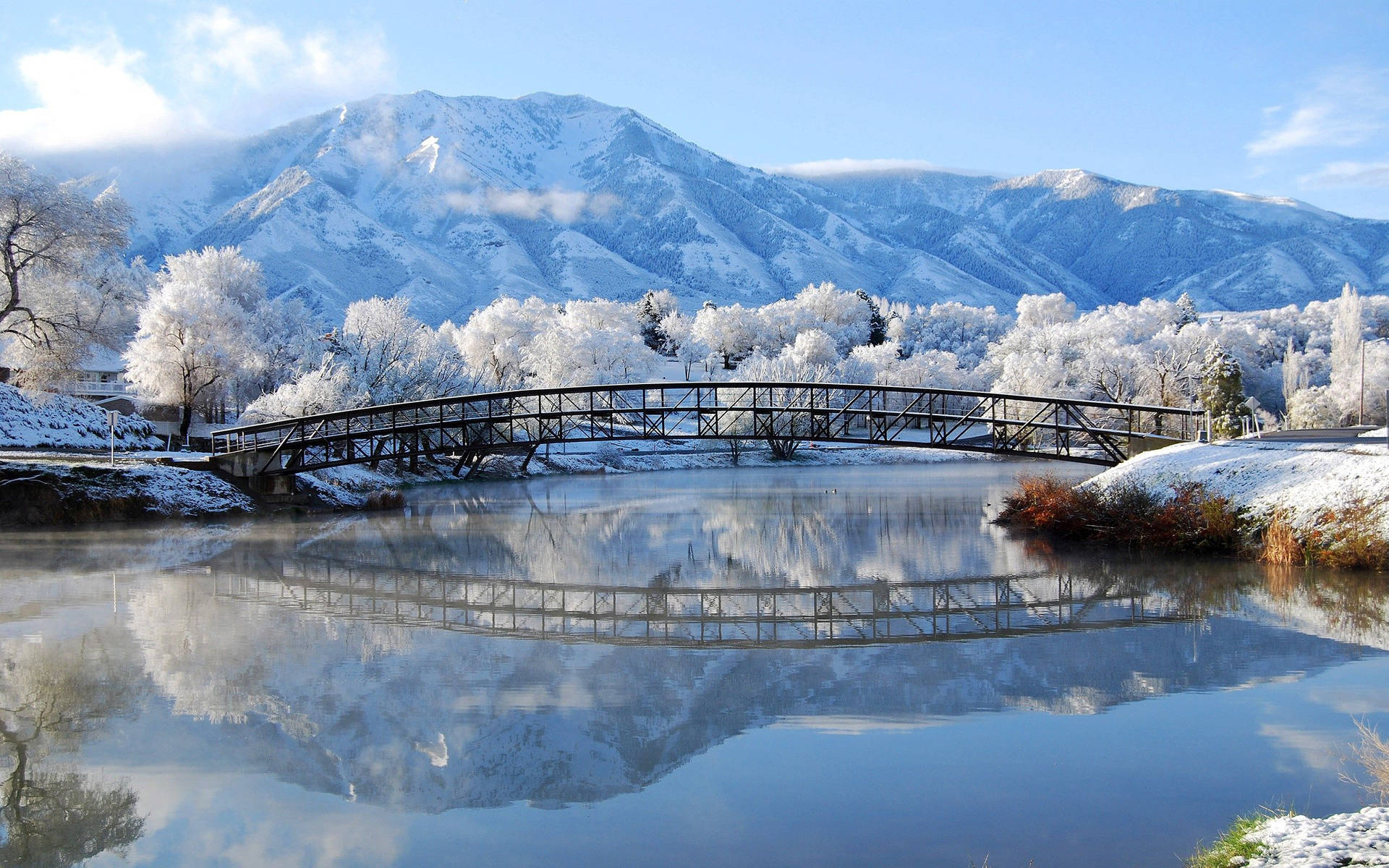 冬季河上雪橋與山巒倒影
