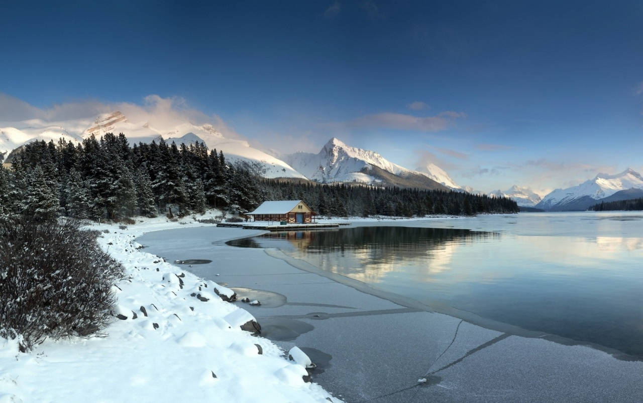 藍天下冰凍湖面上的雪屋，以山為背景