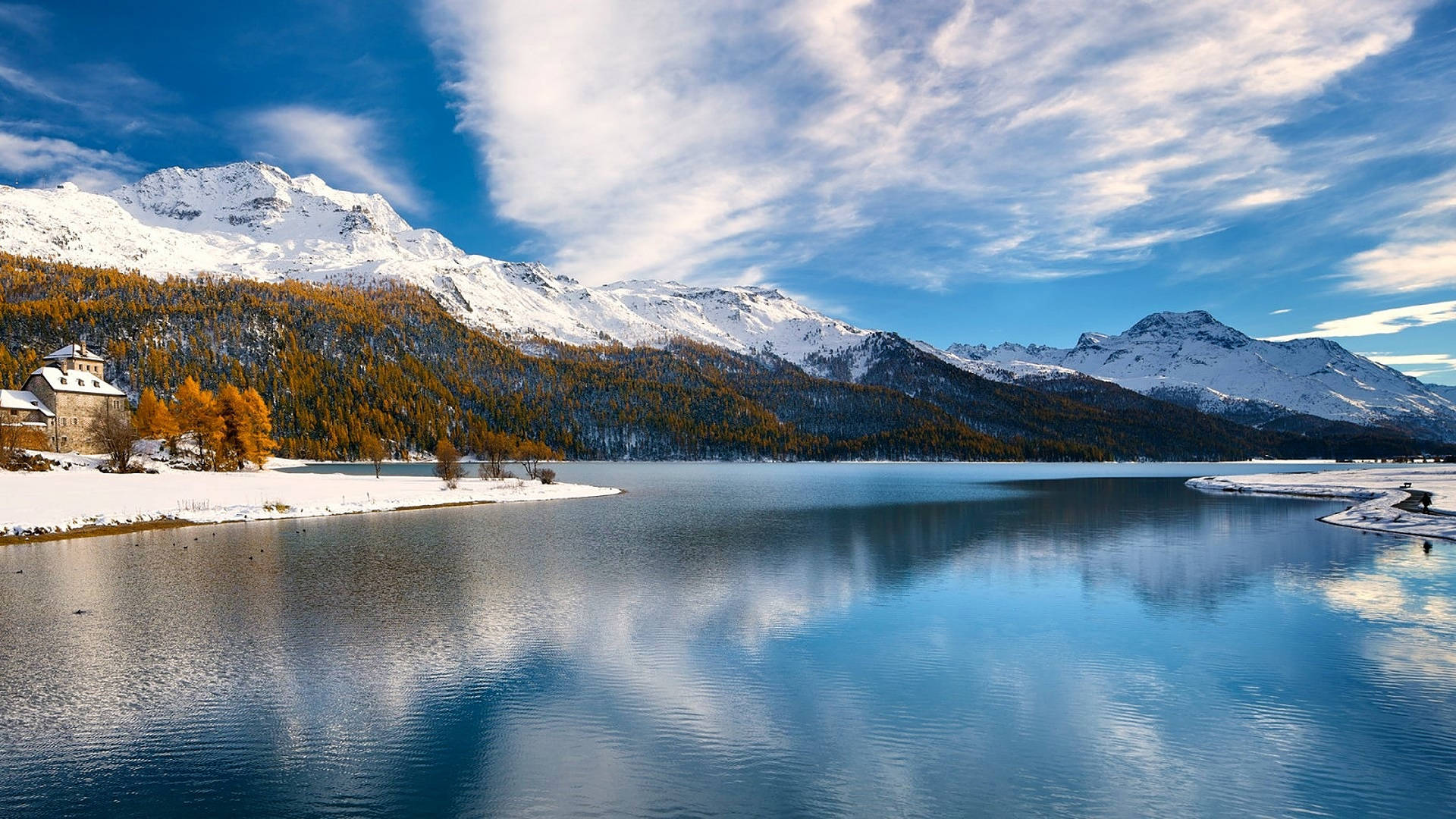 冬季瑞士阿爾卑斯山湖景 壁紙 — 寧靜的冬日湖泊映照著積雪的山峰和帶有縷縷白雲的藍天，在清澈的陽光下。