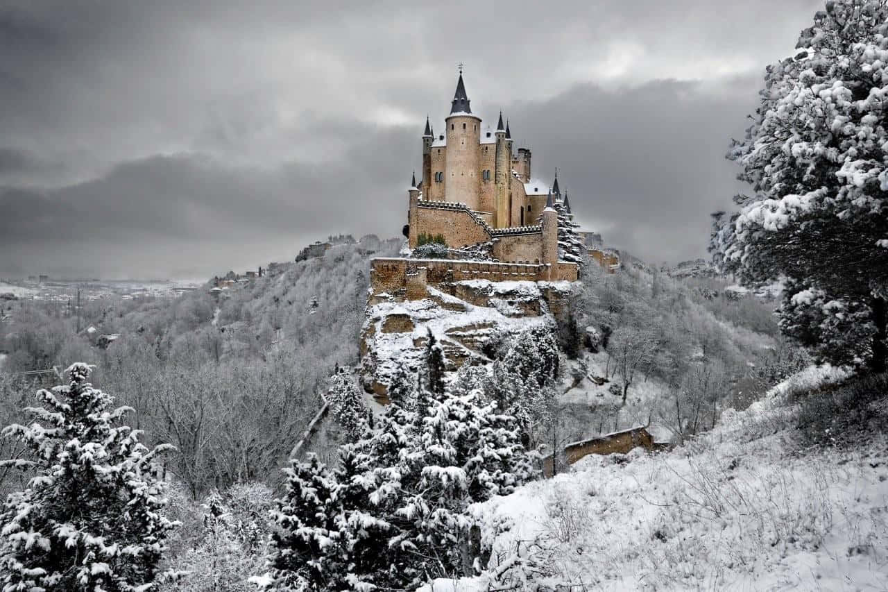 冬日山坡上覆蓋著雪的古老城堡，樹木光禿。