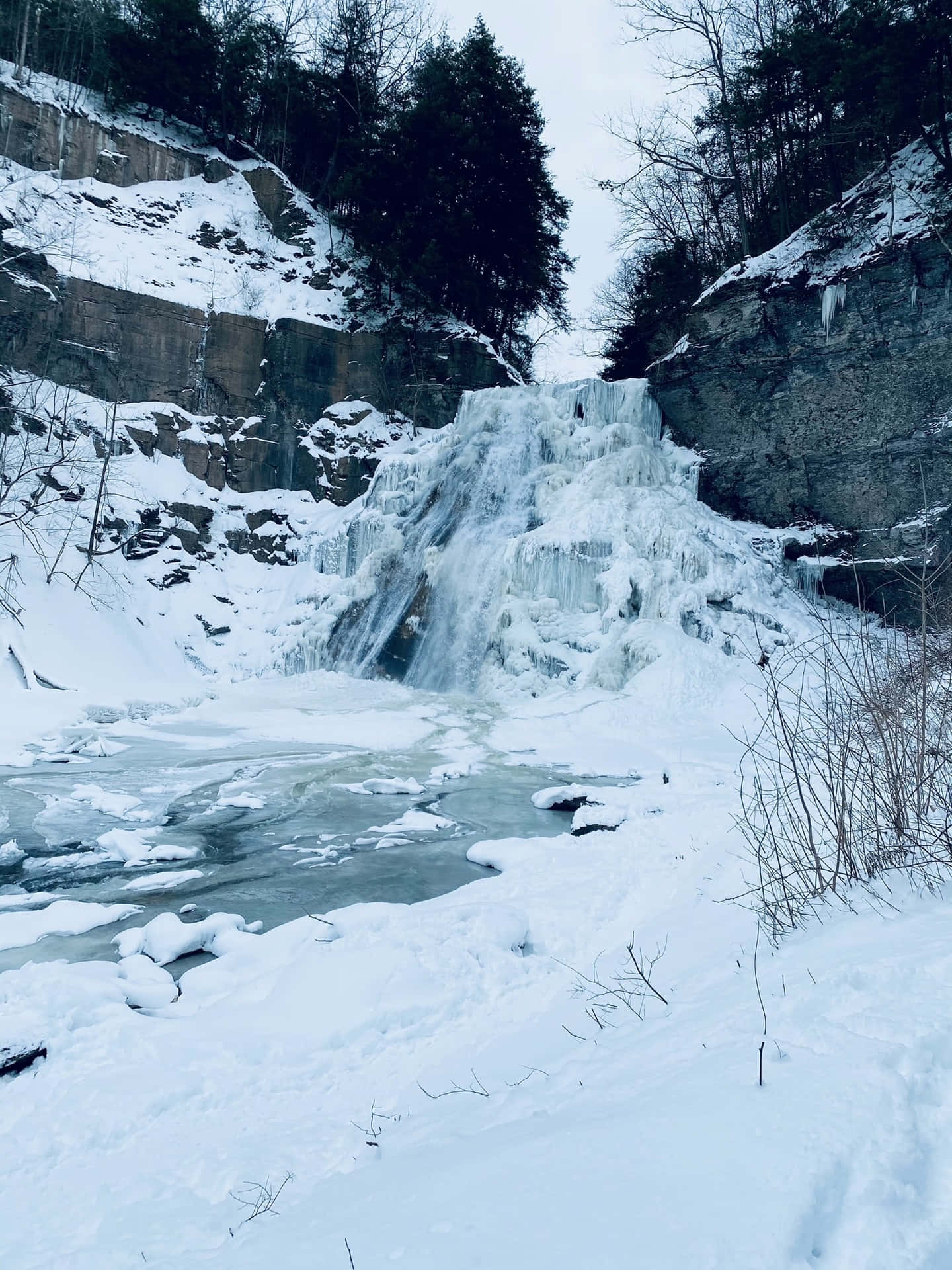 雪地冬季森林中的冰凍瀑布，下方是冰河