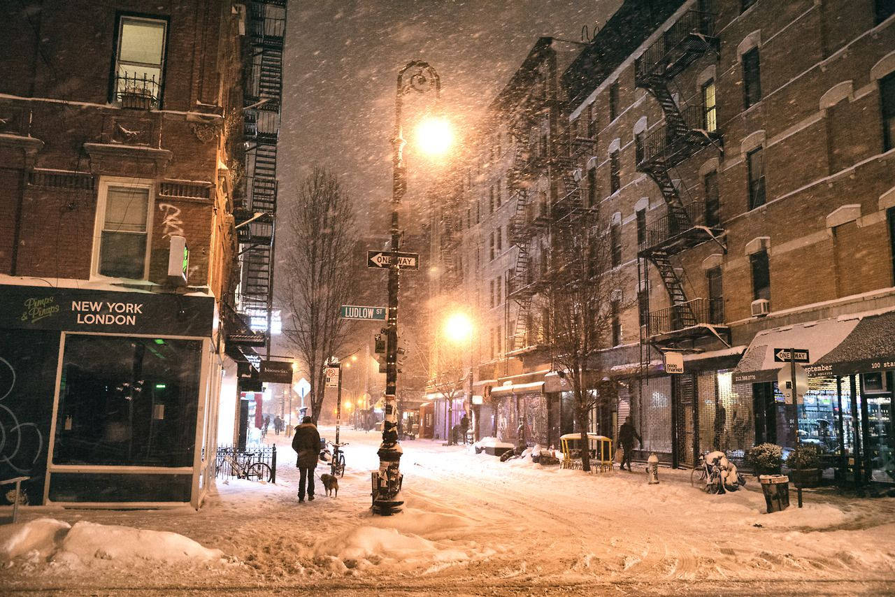 夜晚被雪覆蓋的城市街道，有行人和發光的路燈。