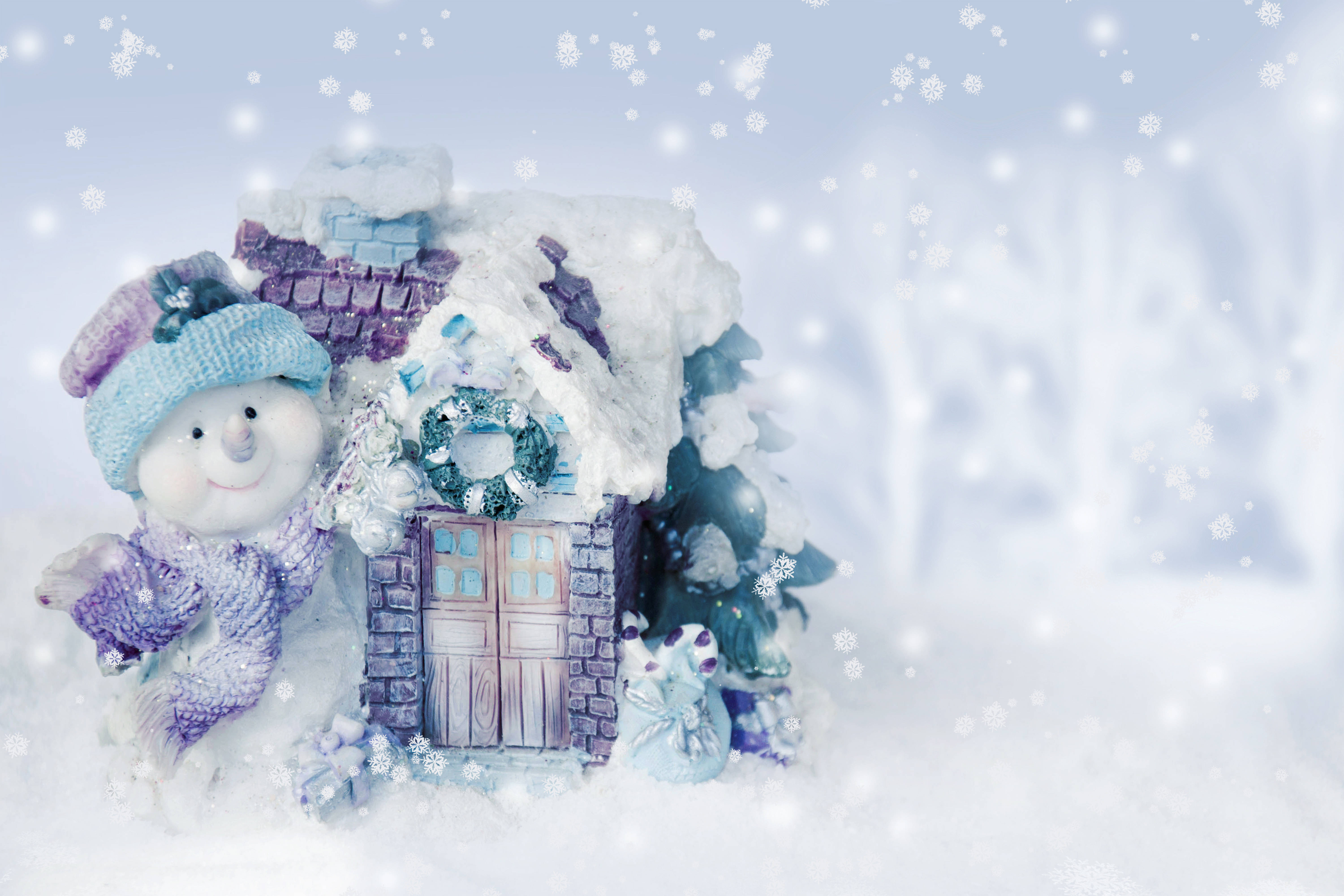冬季雪人裝飾 壁紙 — 一個戴著針織帽的快樂雪人站在一間被雪覆蓋的小屋旁，小屋的門上掛著花環，呈現出白雪皚皚的冬日場景。