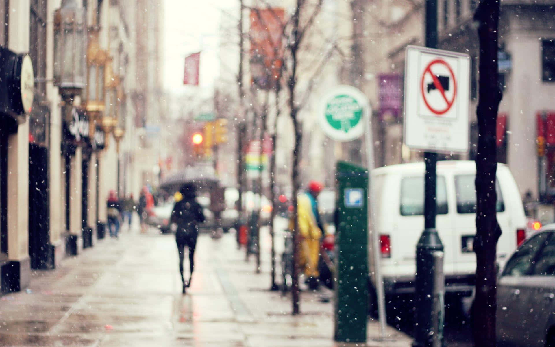 Winter Cityscape 桌布 壁紙 — 冬季雪景中模糊的城市街道場景，一名孤獨的行人沿著濕漉漉的人行道走遠。